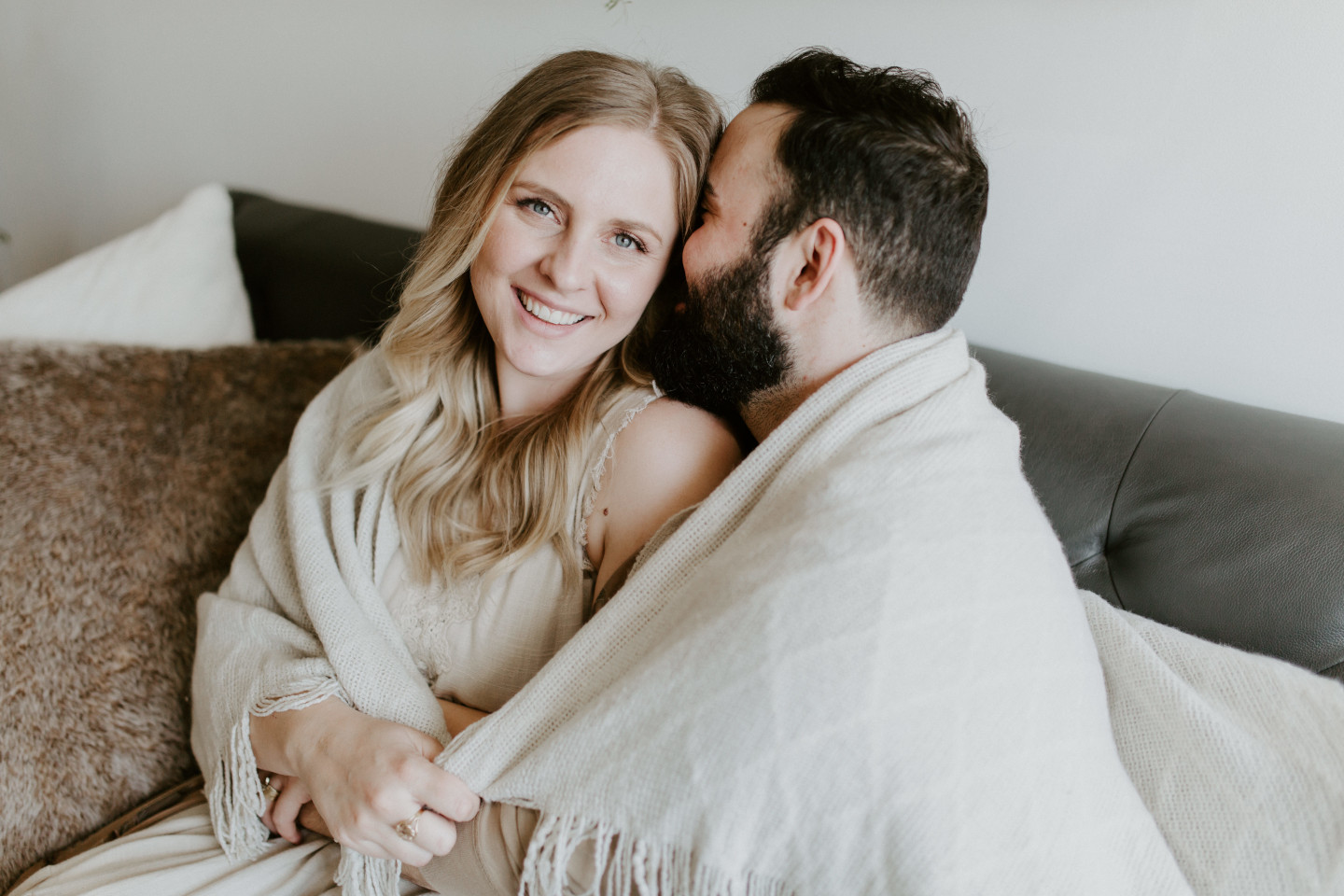 Trevor holds Abigail as they sit on the couch in a Portland, Oregon loft. Lifestyle photography in Portland Oregon by Sienna Plus Josh.