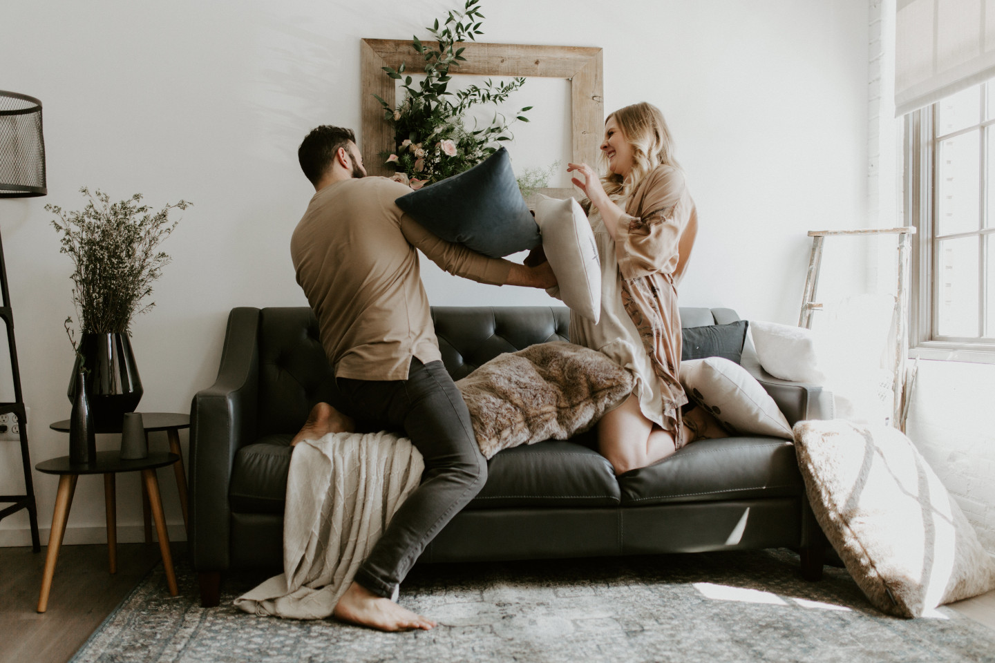 Trevor and Abigail pillow fight on a couch. Lifestyle photography in Portland Oregon by Sienna Plus Josh.