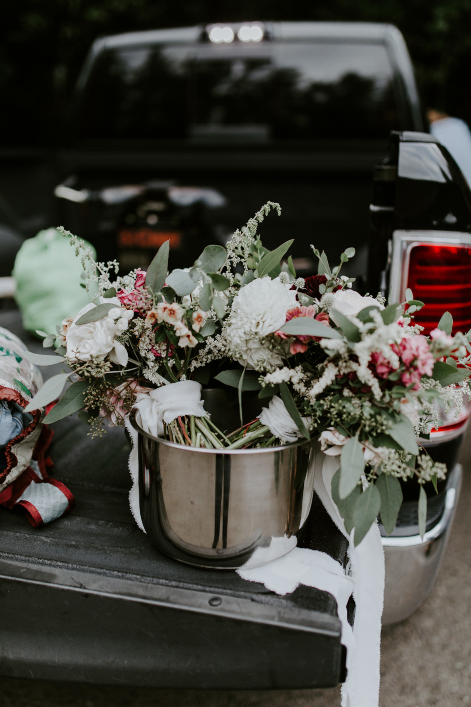 Kate and Nicole's bouquets sit in a pot on a tailgate. Elopement wedding photography at Bridal Veil Falls by Sienna Plus Josh.