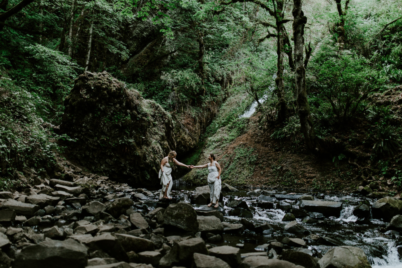 Kate and Audrey make their way across the rocks. Elopement wedding photography at Bridal Veil Falls by Sienna Plus Josh.