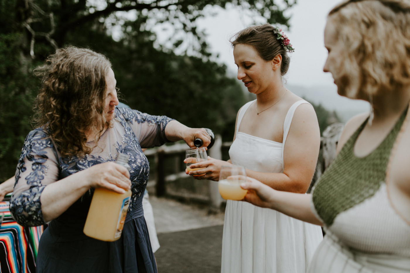 Kate and Audrey have drinks poured for them. Elopement wedding photography at Bridal Veil Falls by Sienna Plus Josh.