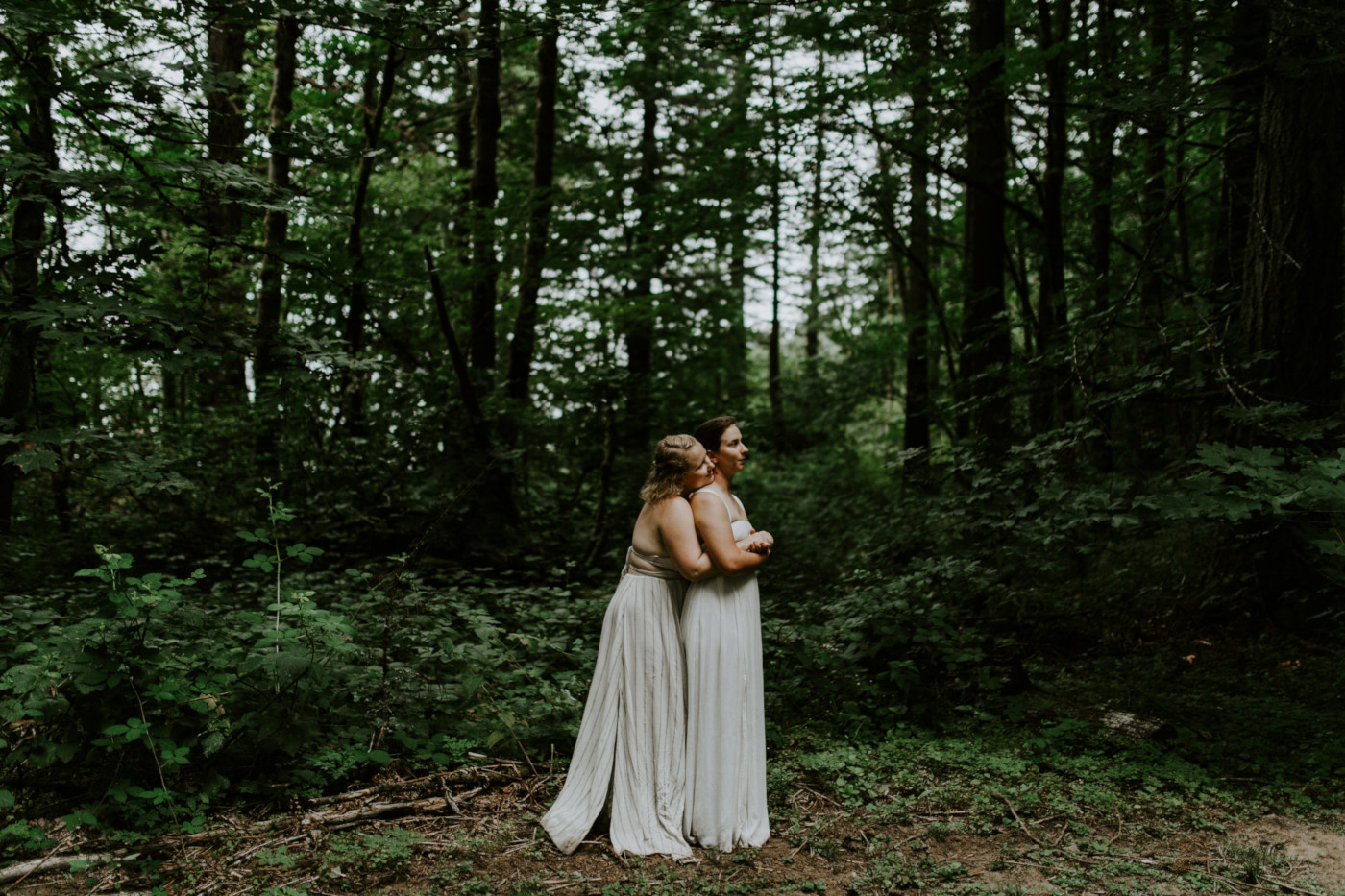 Kate and Audrey hug in front of the forest. Elopement wedding photography at Bridal Veil Falls by Sienna Plus Josh.