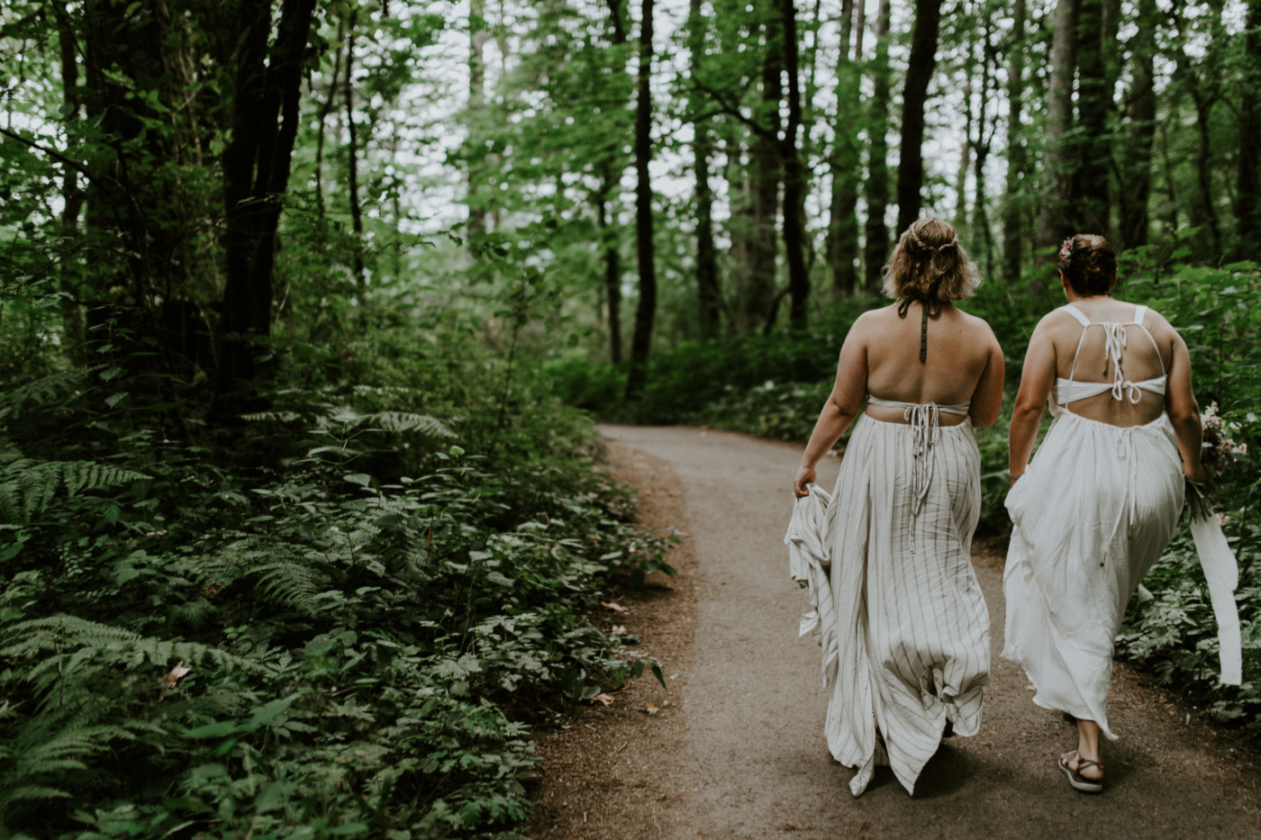 Kate and Audrey walk down a path toward Bridal Veil Falls. Elopement wedding photography at Bridal Veil Falls by Sienna Plus Josh.