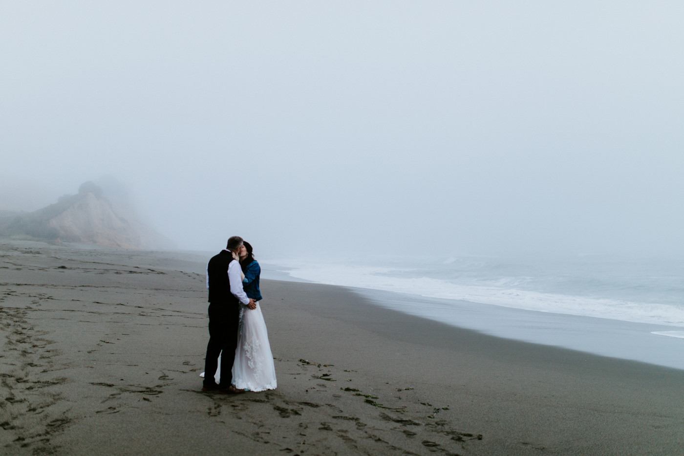 Tim and Hannah kiss on the beach.