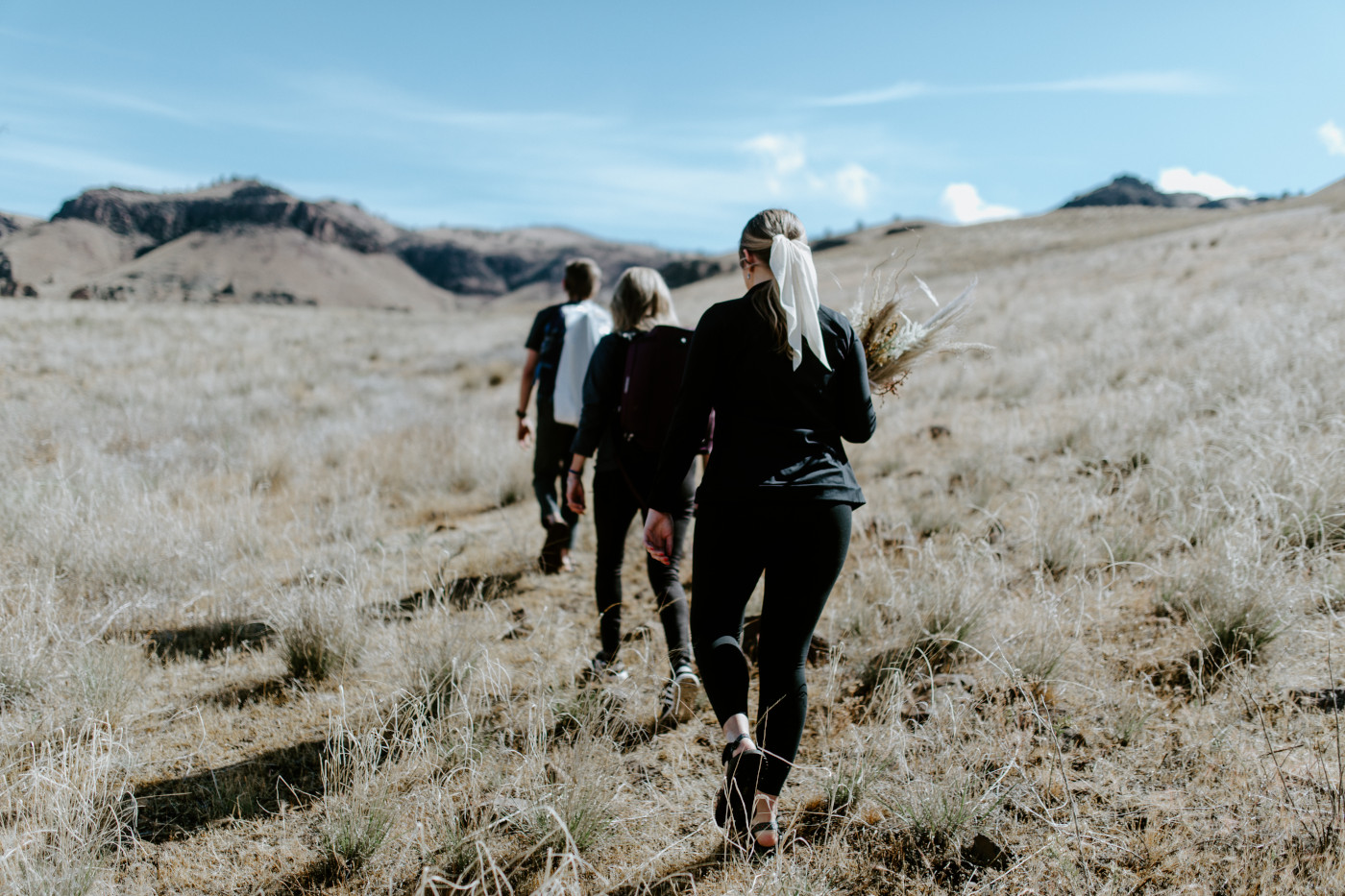 The bridal party hikes out to the elopement spot. Elopement photography in the Central Oregon desert by Sienna Plus Josh.