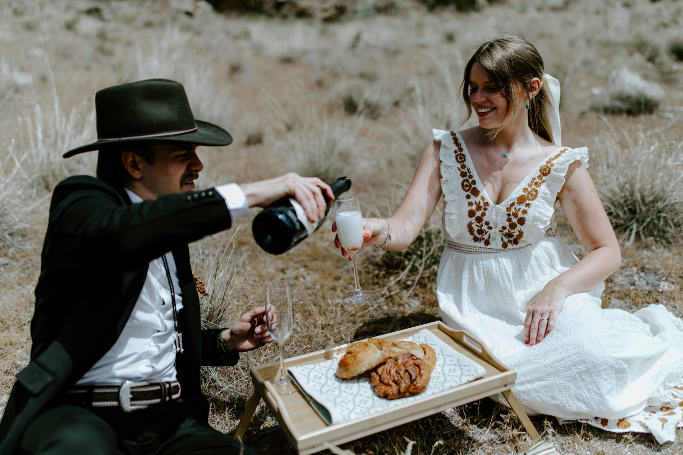 Emily and Greyson pour champagne. Elopement photography in the Central Oregon desert by Sienna Plus Josh.
