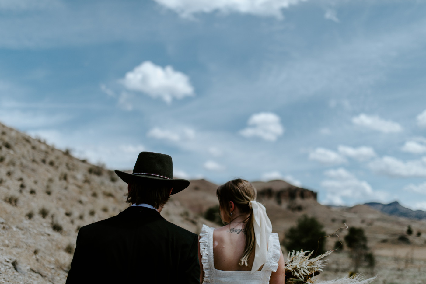 Emily and Greyson look out at the scenery. Elopement photography in the Central Oregon desert by Sienna Plus Josh.