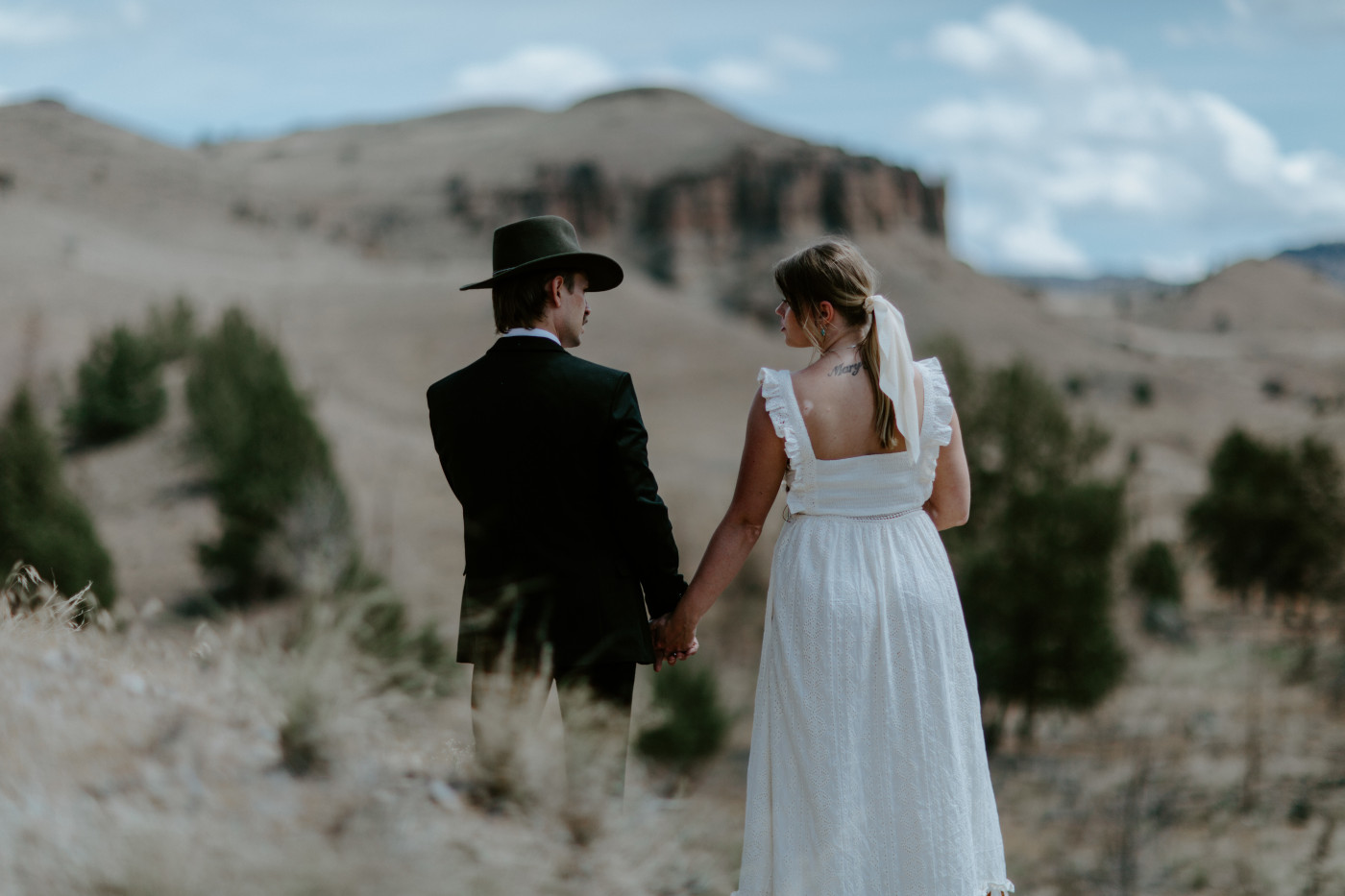 Greyson and Emily hold hands. Elopement photography in the Central Oregon desert by Sienna Plus Josh.