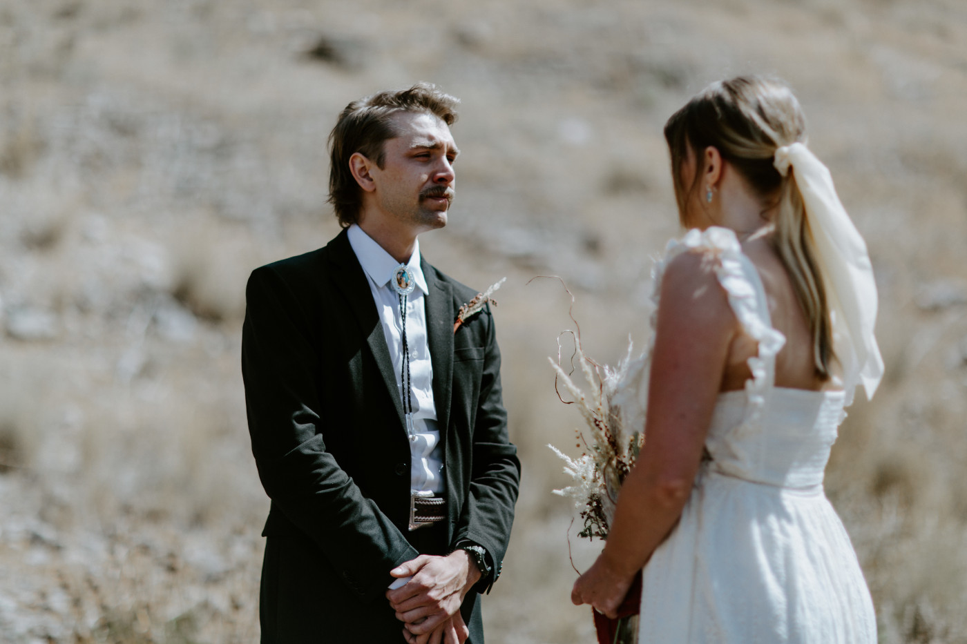 Greyson listens to Emily during their ceremony. Elopement photography in the Central Oregon desert by Sienna Plus Josh.
