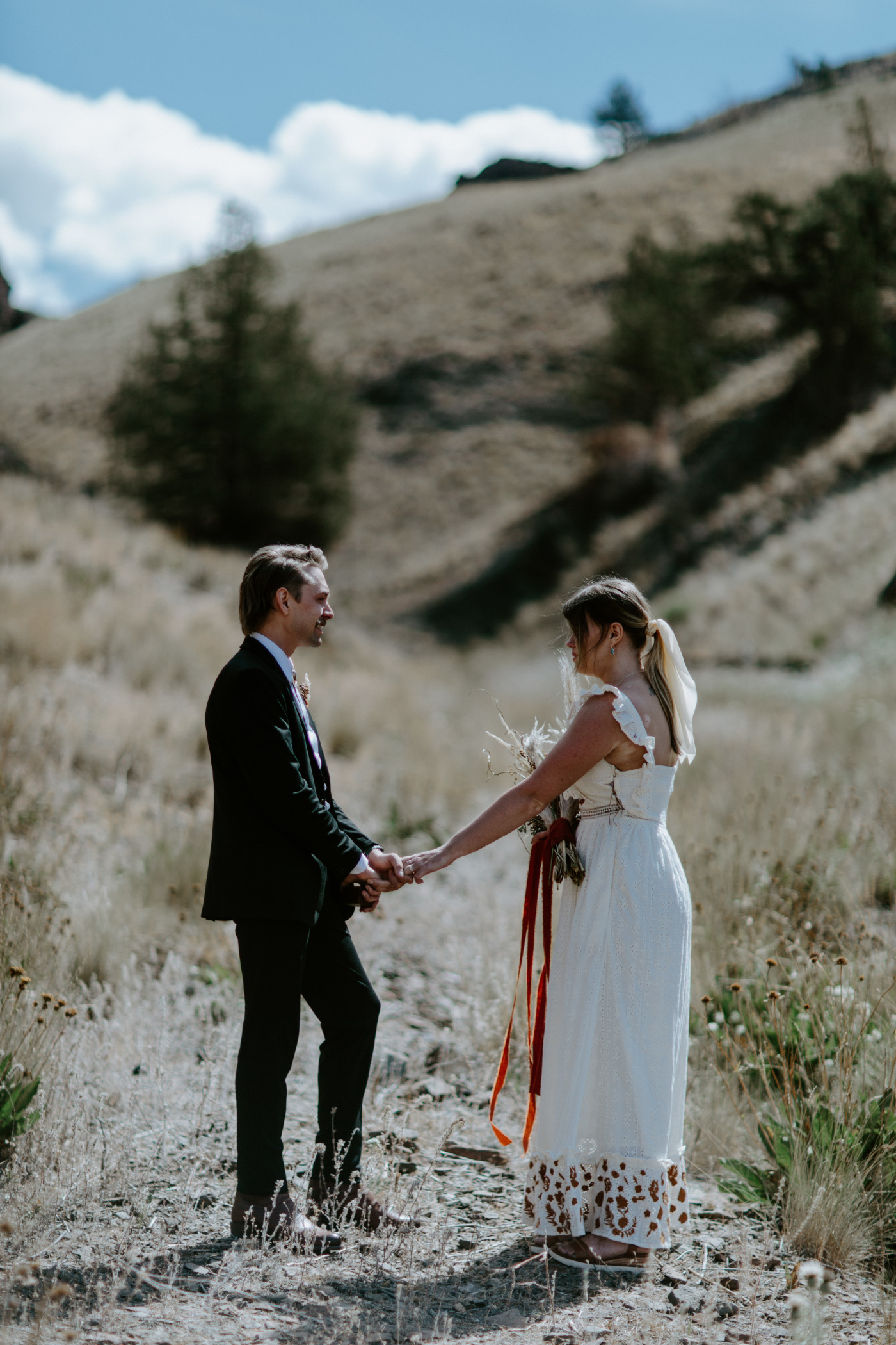 Greyson and Emily hold hands during their elopement ceremony. Elopement photography in the Central Oregon desert by Sienna Plus Josh.