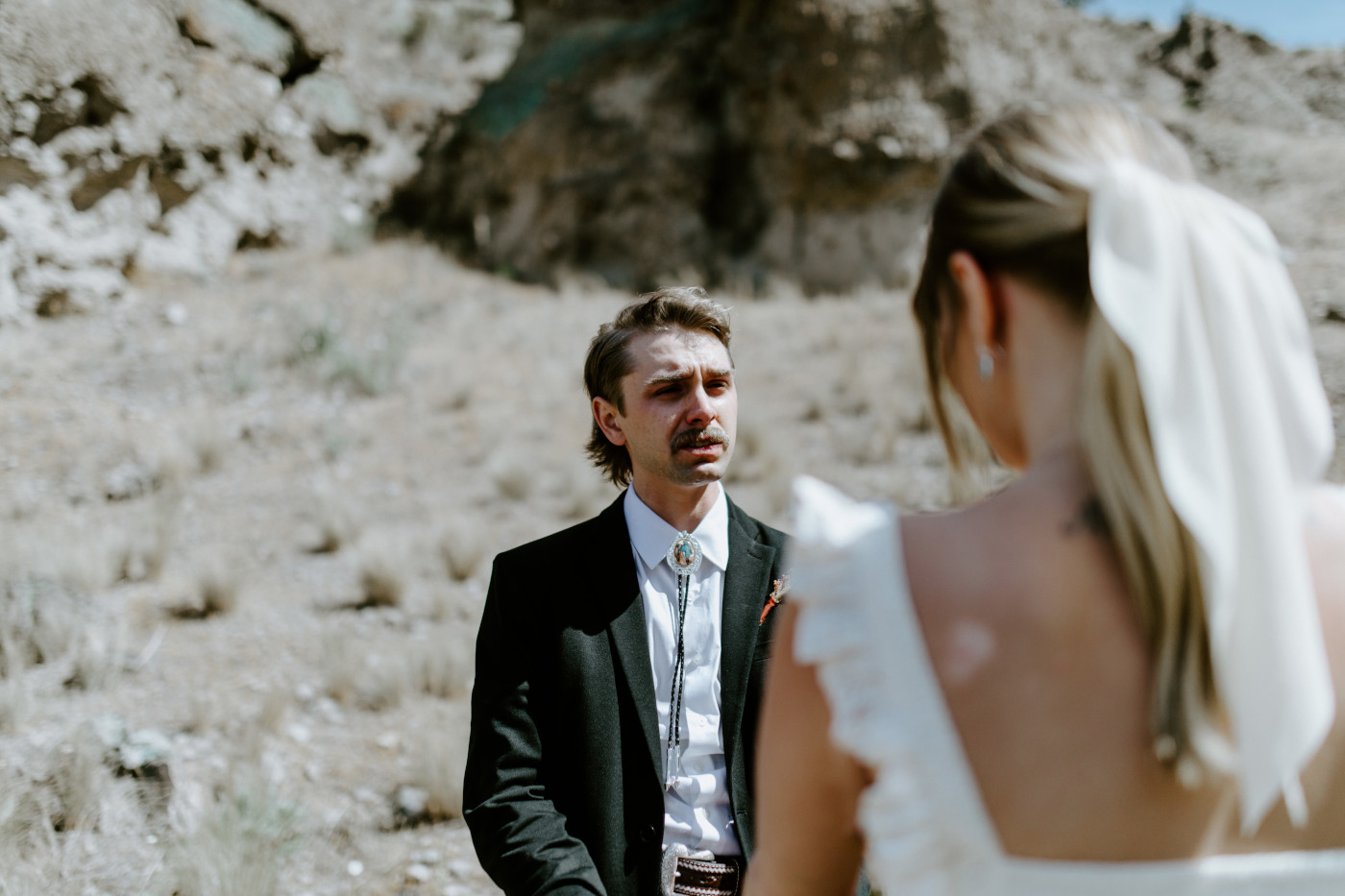 Greyson holds Emily's hand to exchange rings. Elopement photography in the Central Oregon desert by Sienna Plus Josh.