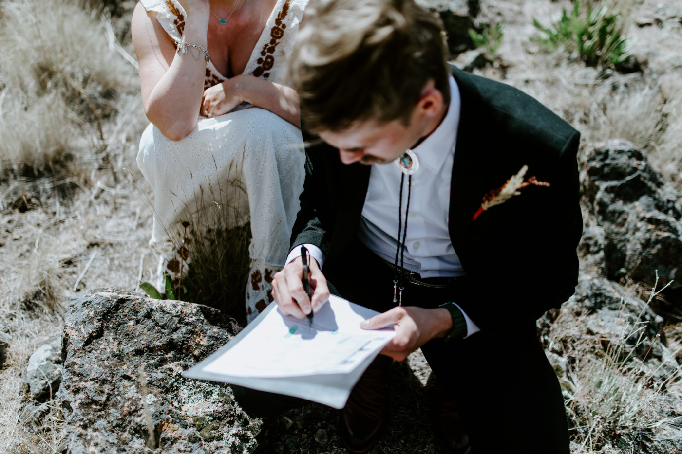 Greyson and Emily finalizing their elopement ceremony with paperwork. Elopement photography in the Central Oregon desert by Sienna Plus Josh.
