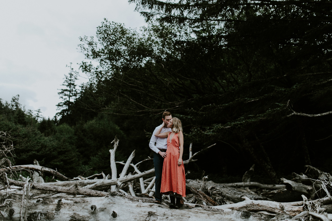 Billy and Chelsey stand on a fallen tree. Elopement wedding photography at Cannon Beach by Sienna Plus Josh.