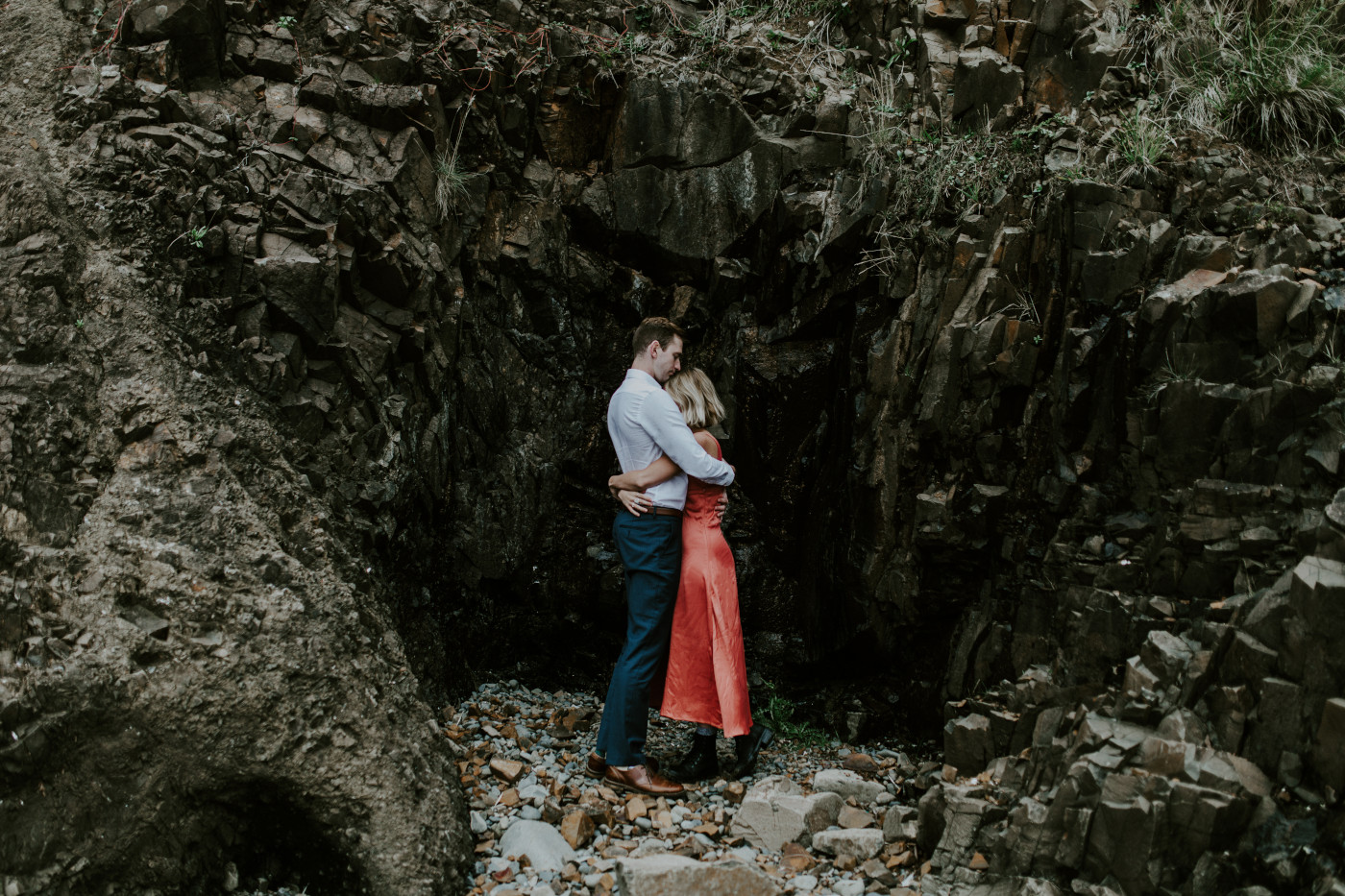 Chelsey and Billy hug next to a cliff. Elopement wedding photography at Cannon Beach by Sienna Plus Josh.