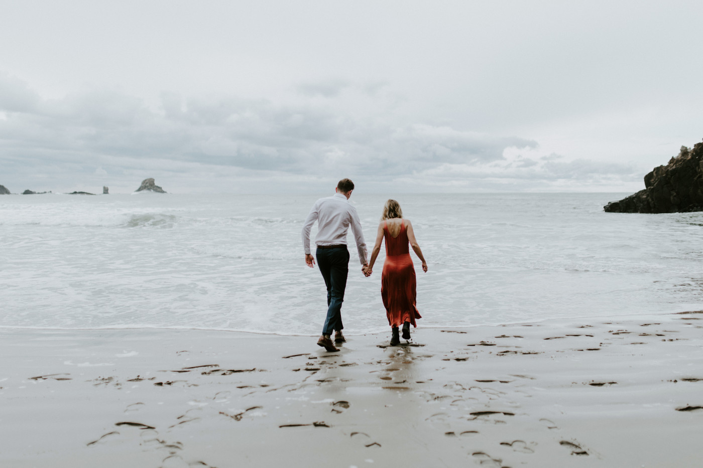 Chelsey and Billy walk toward the ocean. Elopement wedding photography at Cannon Beach by Sienna Plus Josh.
