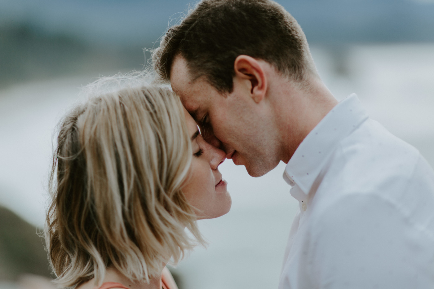 Billy and Chelsey stand forehead to forehead. Elopement wedding photography at Cannon Beach by Sienna Plus Josh.
