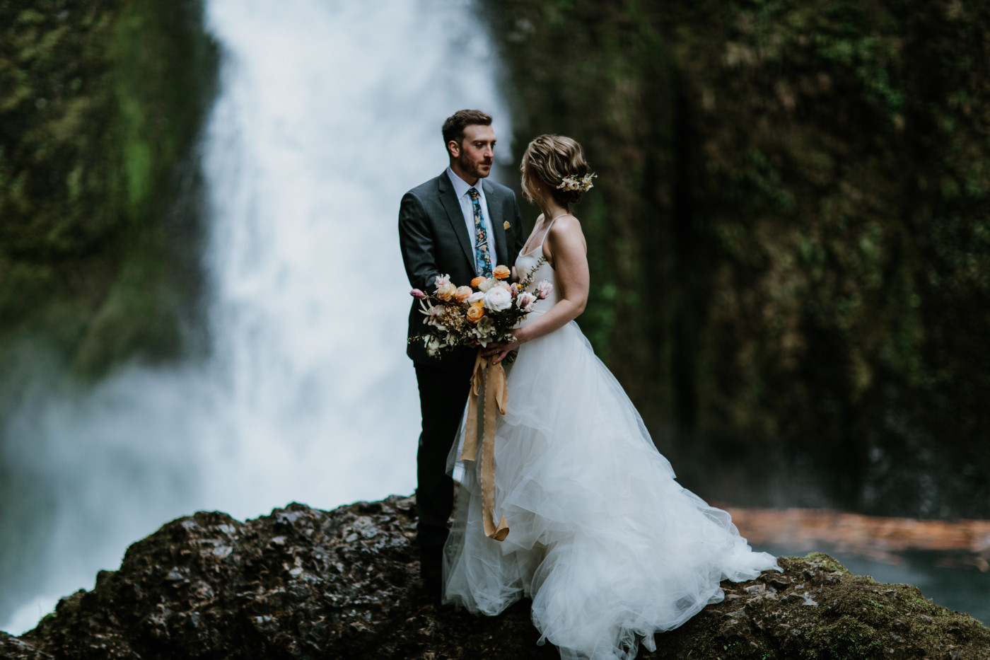 Lennie and Allison stand in front of a waterfall. Elopement photography at Columbia River Gorge by Sienna Plus Josh.