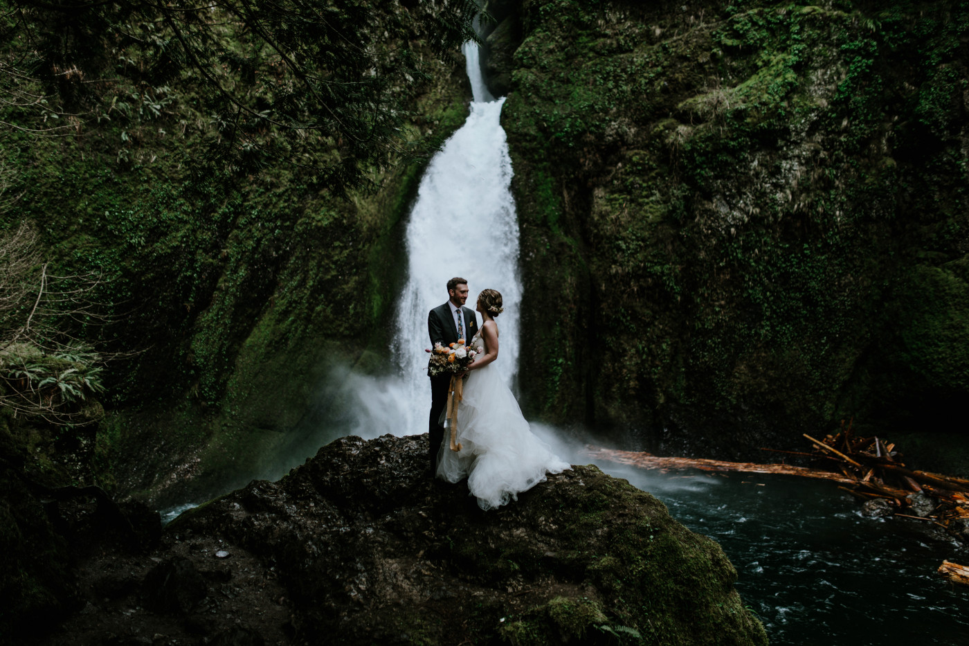 Lennie and Allison stand near a waterfall. Elopement photography at Columbia River Gorge by Sienna Plus Josh.