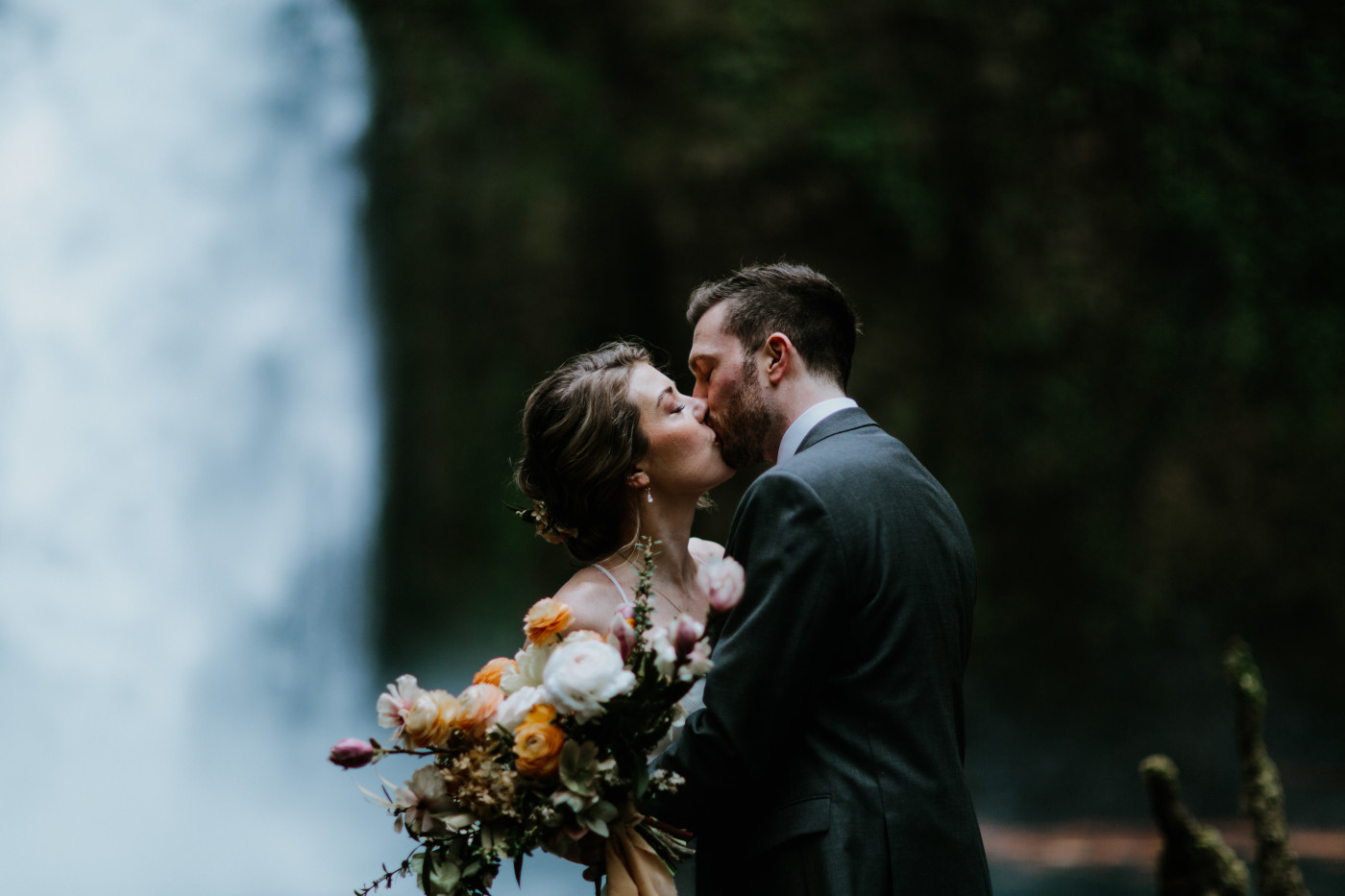 Allison and Lennie kiss in front of a waterfall. Elopement photography at Columbia River Gorge by Sienna Plus Josh.