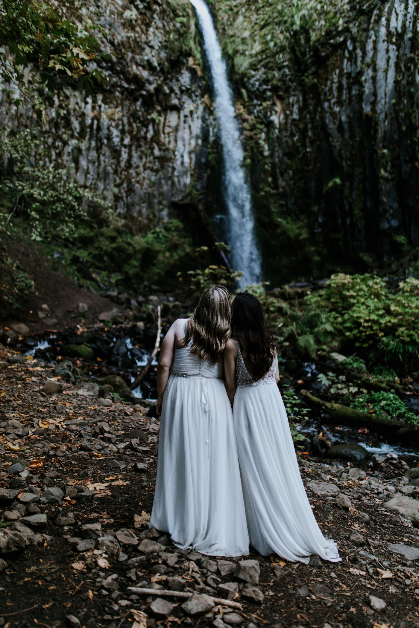 Tiffany and Hayley look at the waterfall. Elopement photography at the Columbia River Gorge by Sienna Plus Josh.