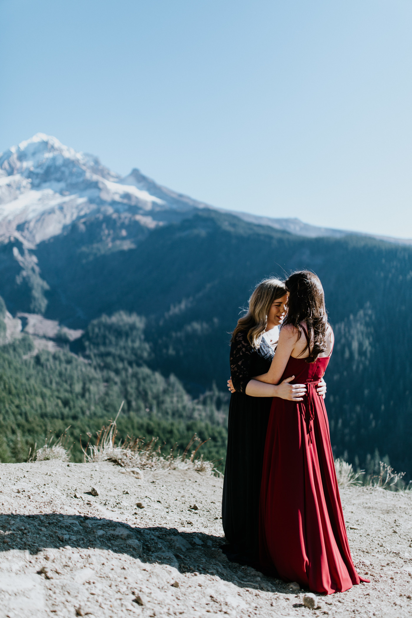 Tiffany and Hayley stand near a cliff with a view of Mt Hood in the background. Elopement photography at the Columbia River Gorge by Sienna Plus Josh.