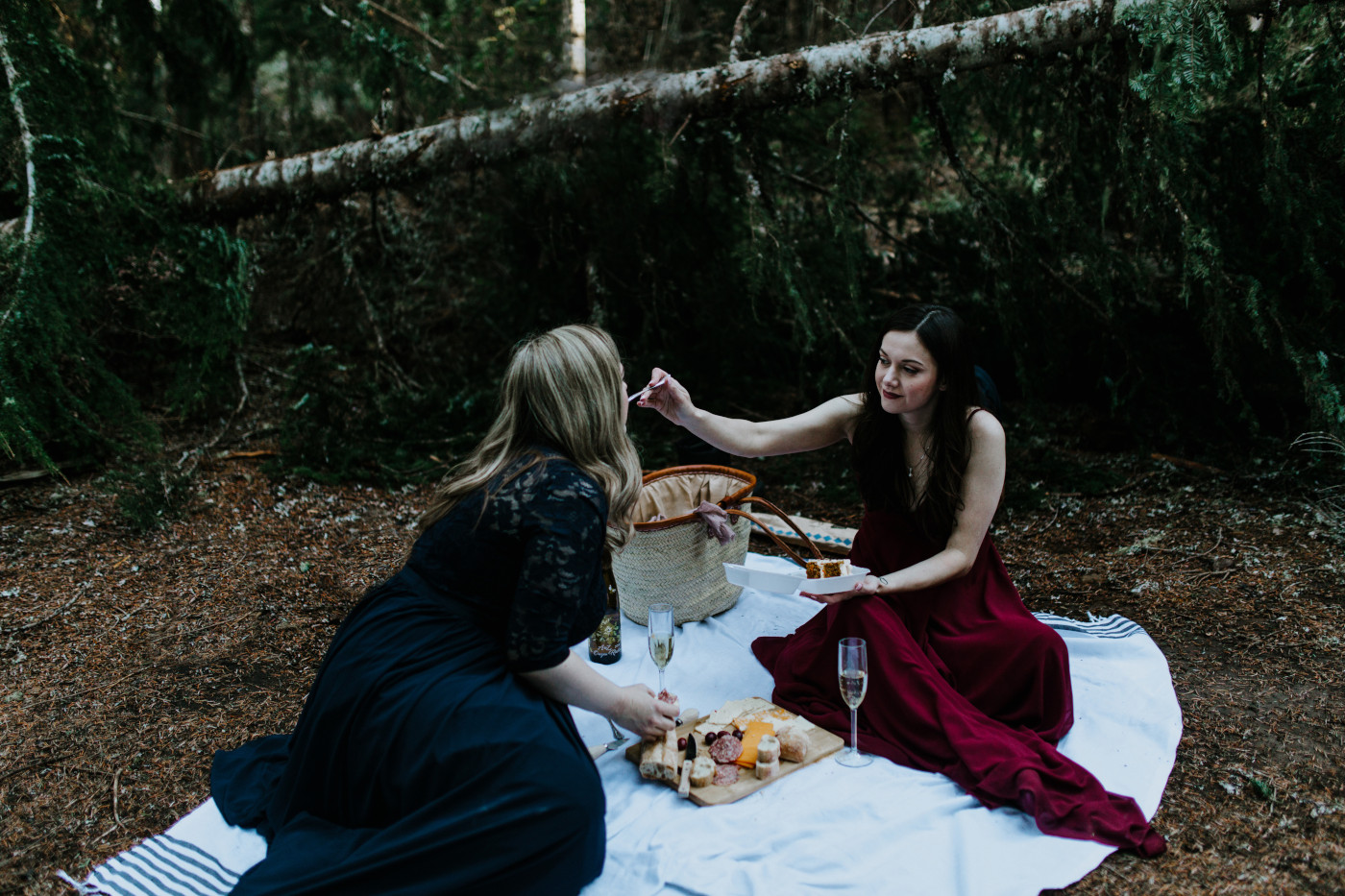 Tiffany feeds Hayley food from the picnic. Elopement photography at the Columbia River Gorge by Sienna Plus Josh.