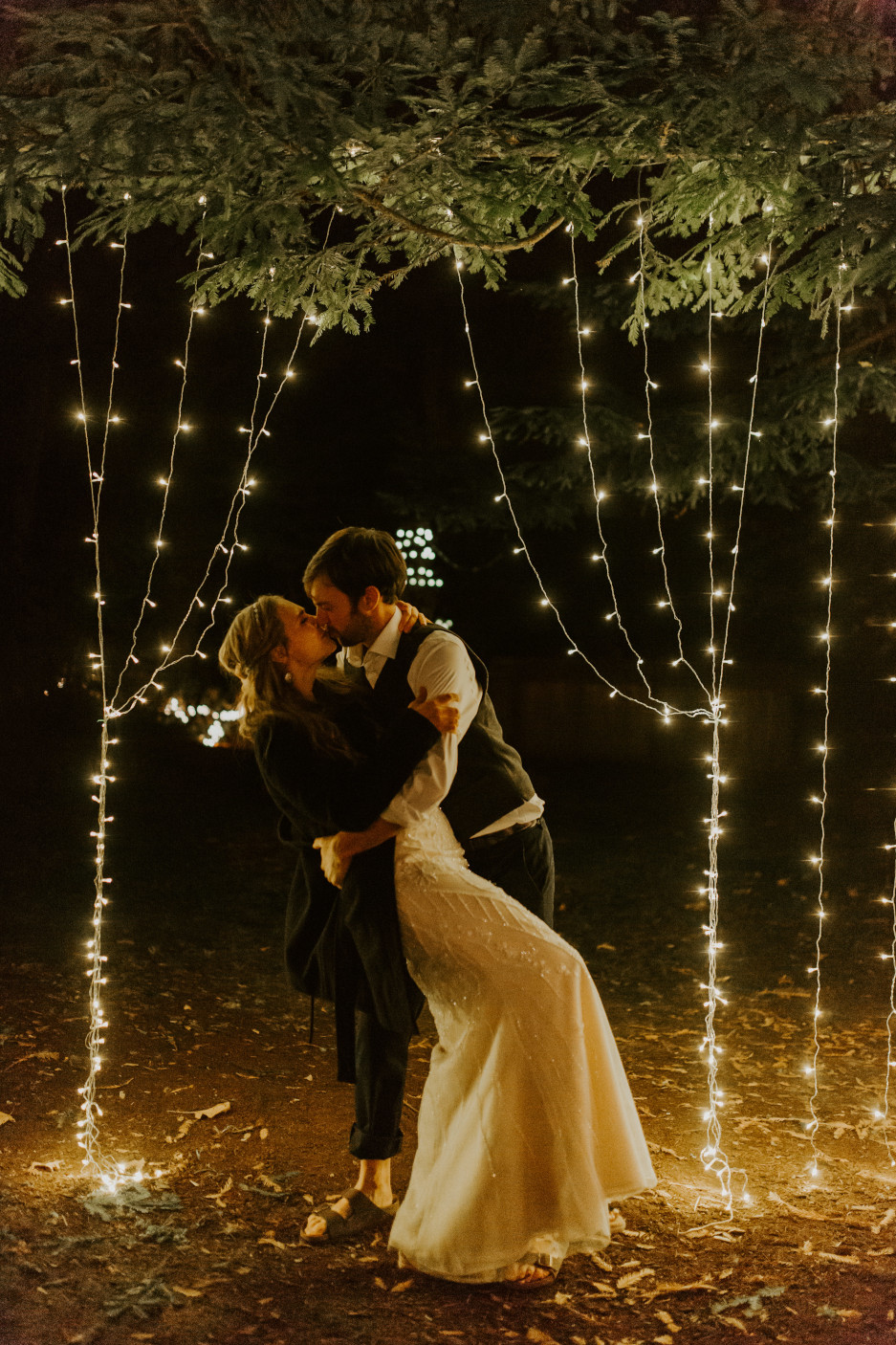 Hannah and Dan kiss in front of lights in Corvallis, Oregon. Intimate wedding photography in Corvallis Oregon by Sienna Plus Josh.