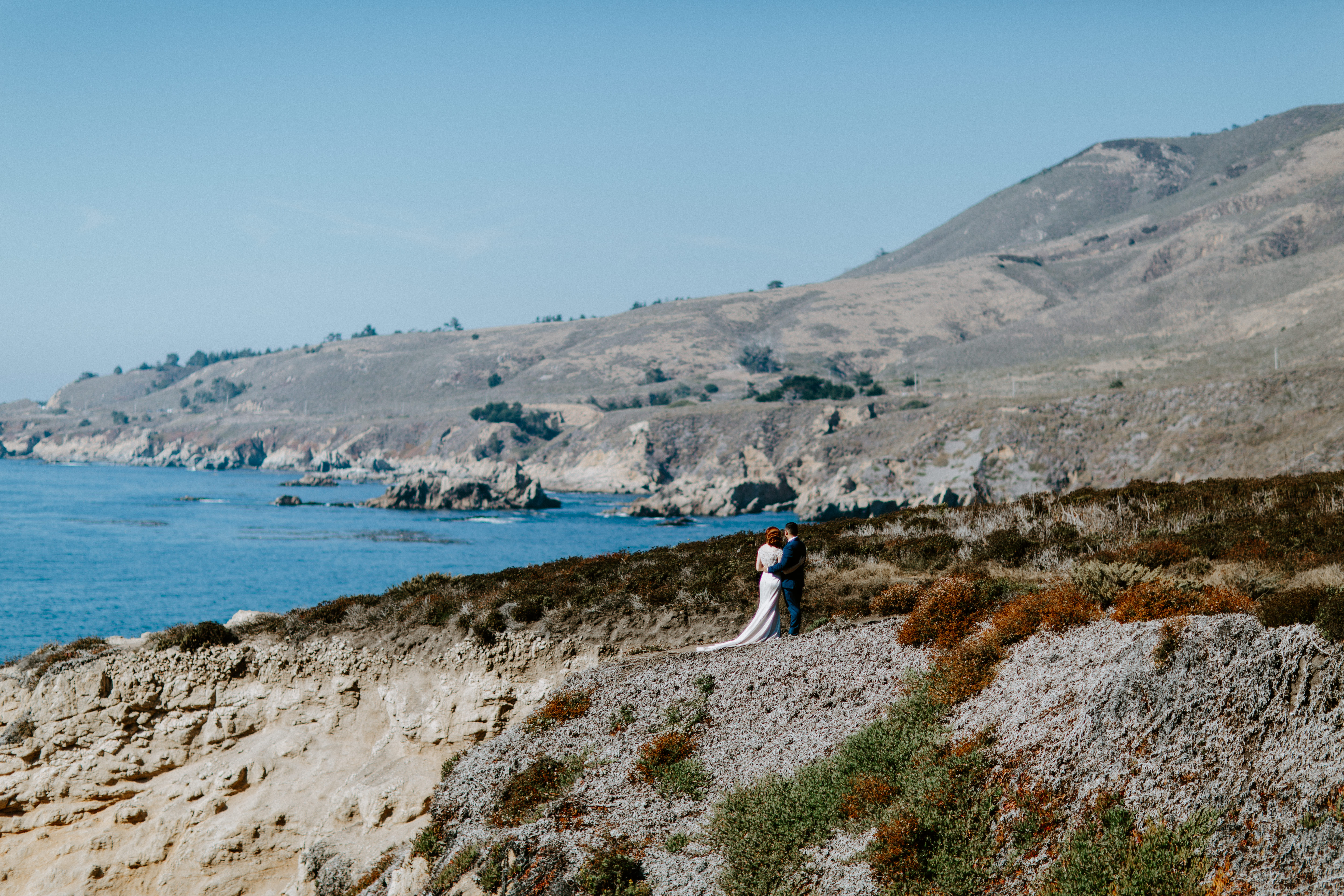 A couple stands along the cliff line in Big Sur, California.