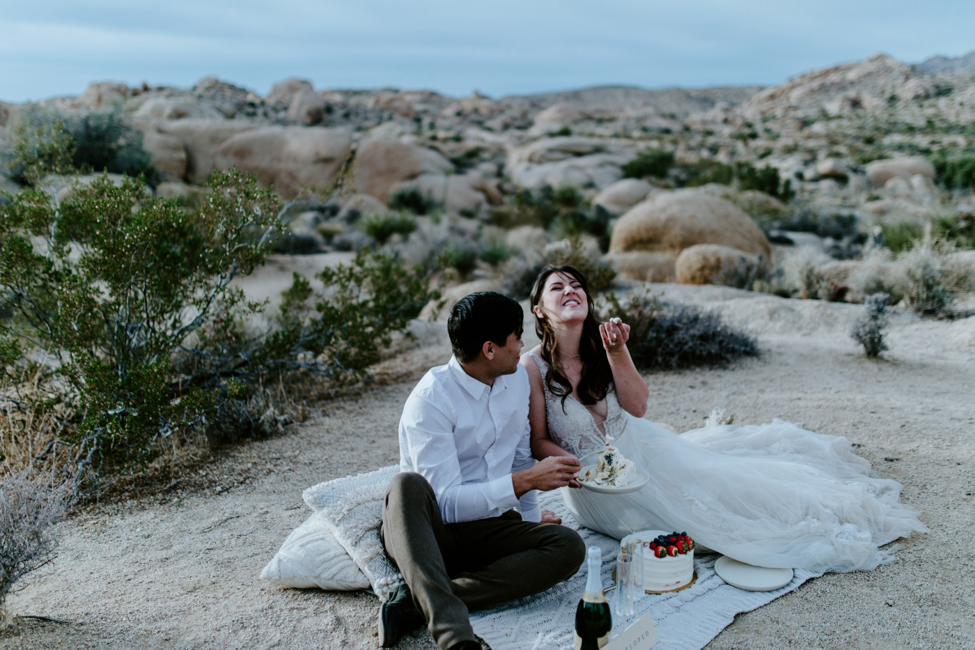 Shelby and Zack enjoy their cake while sitting in Joshua Tree.