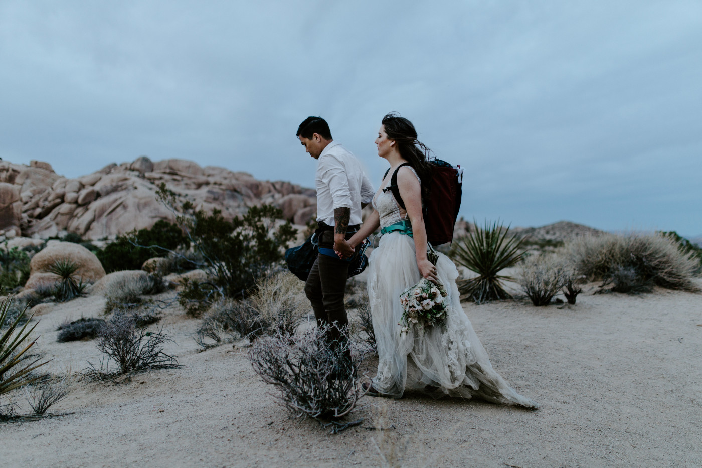 Shelby and Zack hold hands as they walk through Joshua Tree National Park.