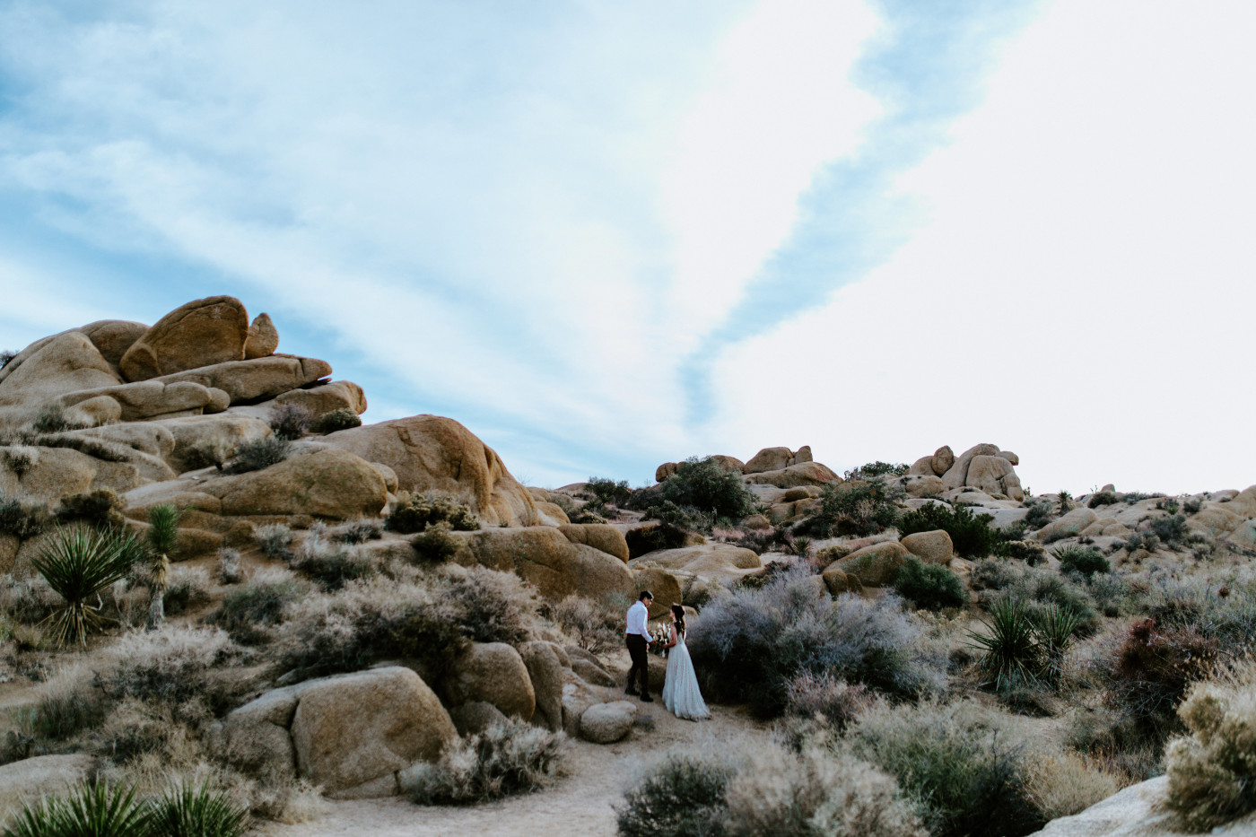 Shelby and Zack stand amongst the boulders in Joshua Tree National Park.