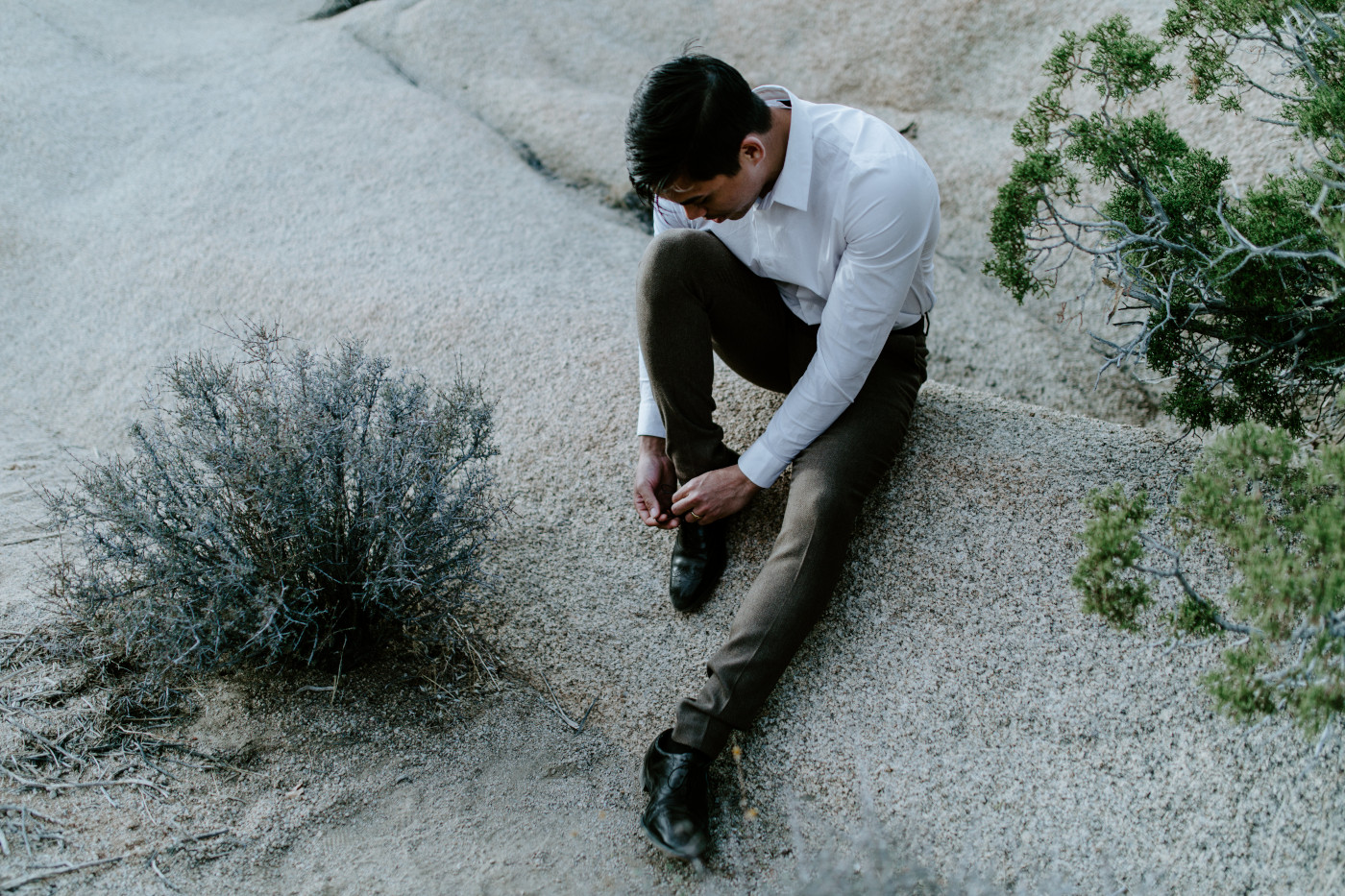 Zack ties his shoe while sitting on a rock in Joshua Tree National Park.