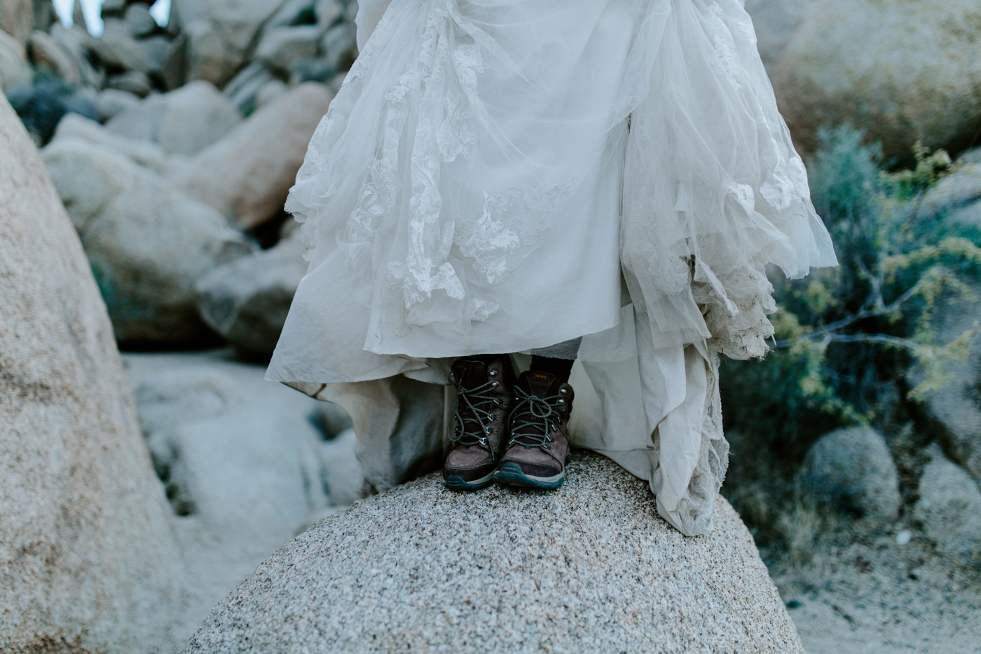 Shelby shoes off her hiking boots with her wedding dress on her elopement day.