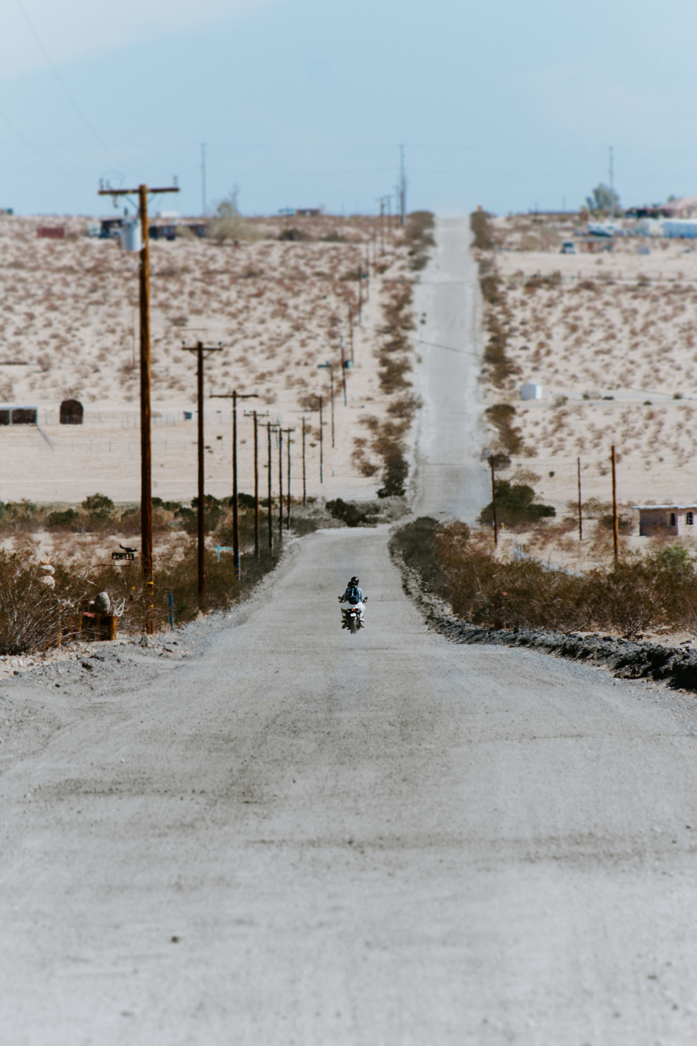 Madison and Becca ride off a long winding road in the Joshua Tree dessert on a motorcycle.