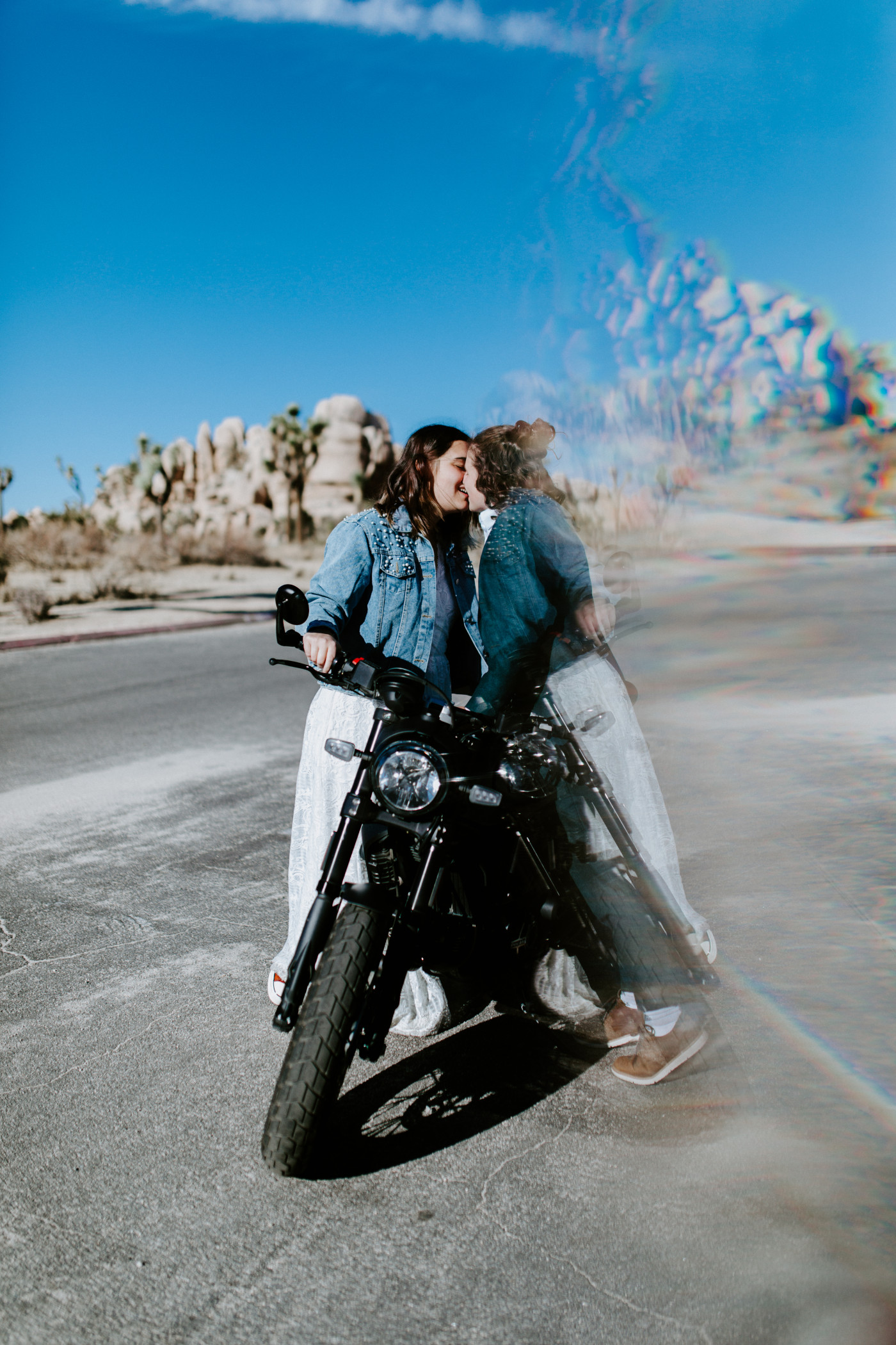 Madison and Becca stand kiss while standing near their motorcycle.