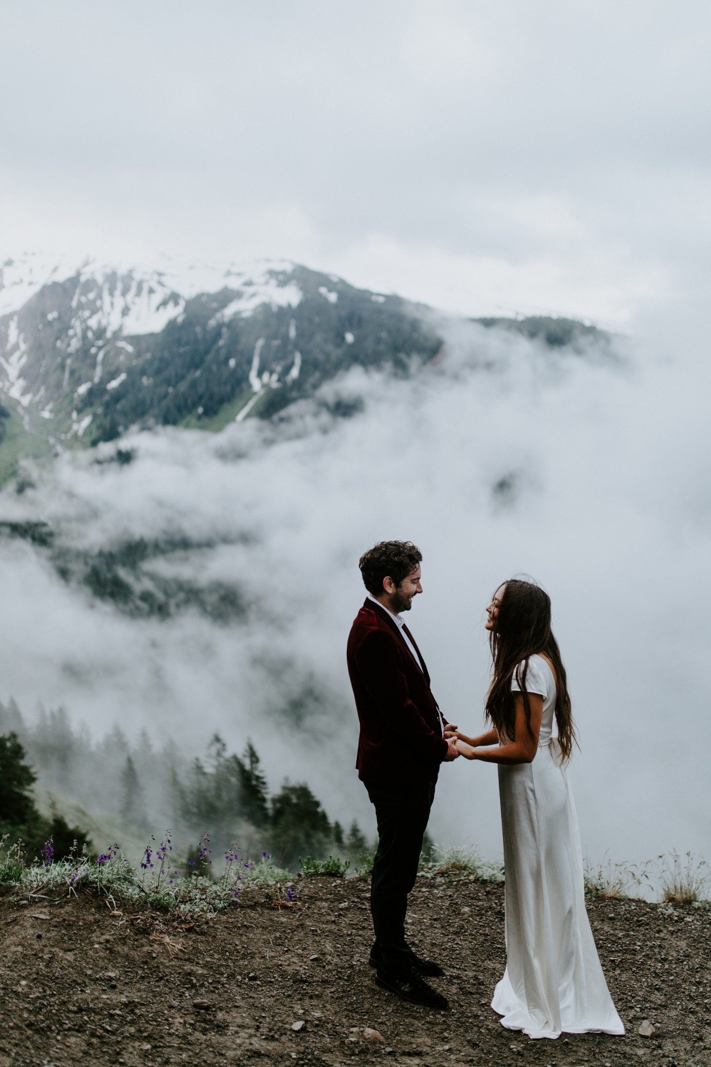 Murray and Katelyn stand near a cliff with the clouds and Mount Hood in the background. Elopement wedding photography at Mount Hood by Sienna Plus Josh.