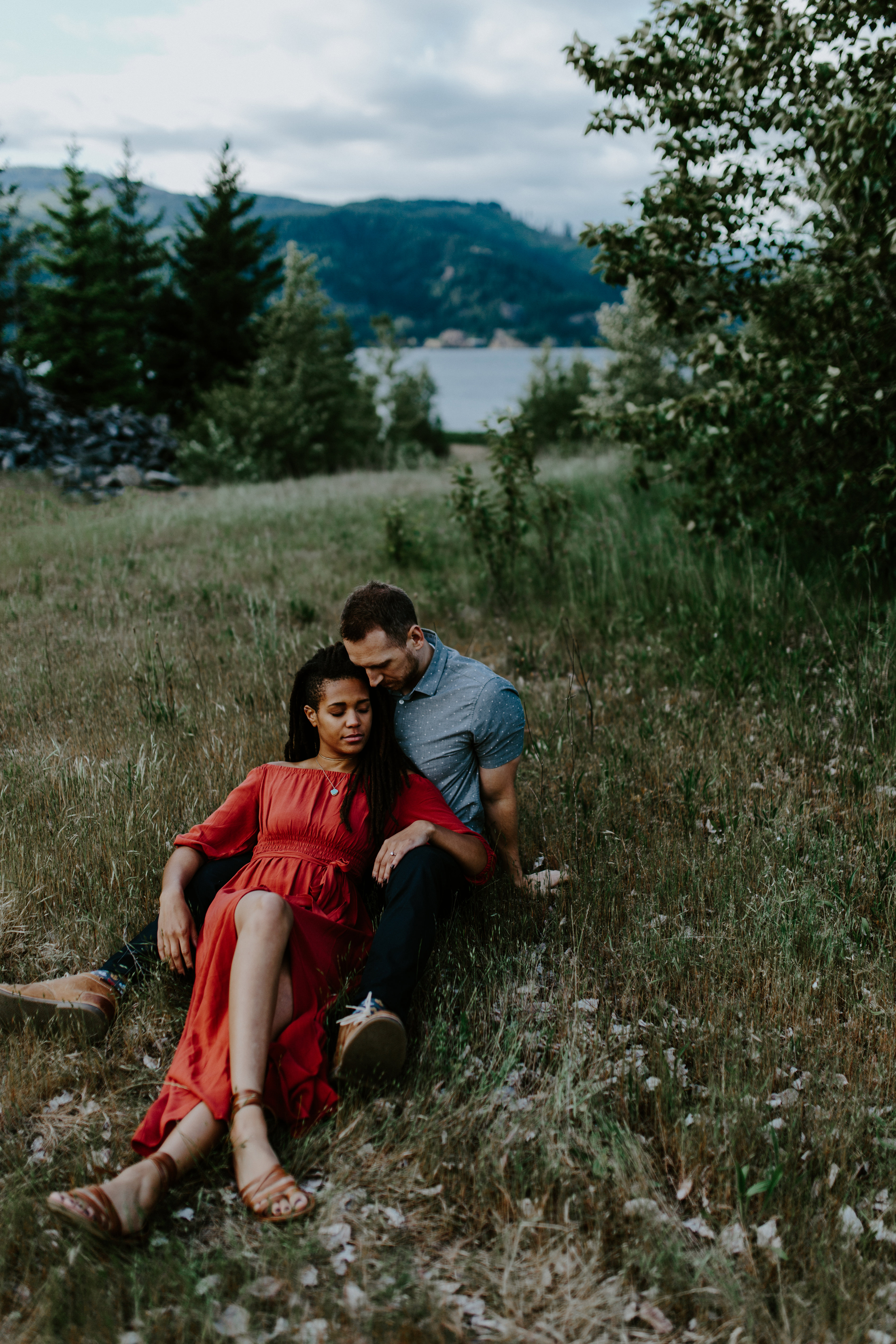 Kayloni and Garrett rest on the grass in the Columbia River Gorge, Oregon. Engagement photography in Portland Oregon by Sienna Plus Josh.