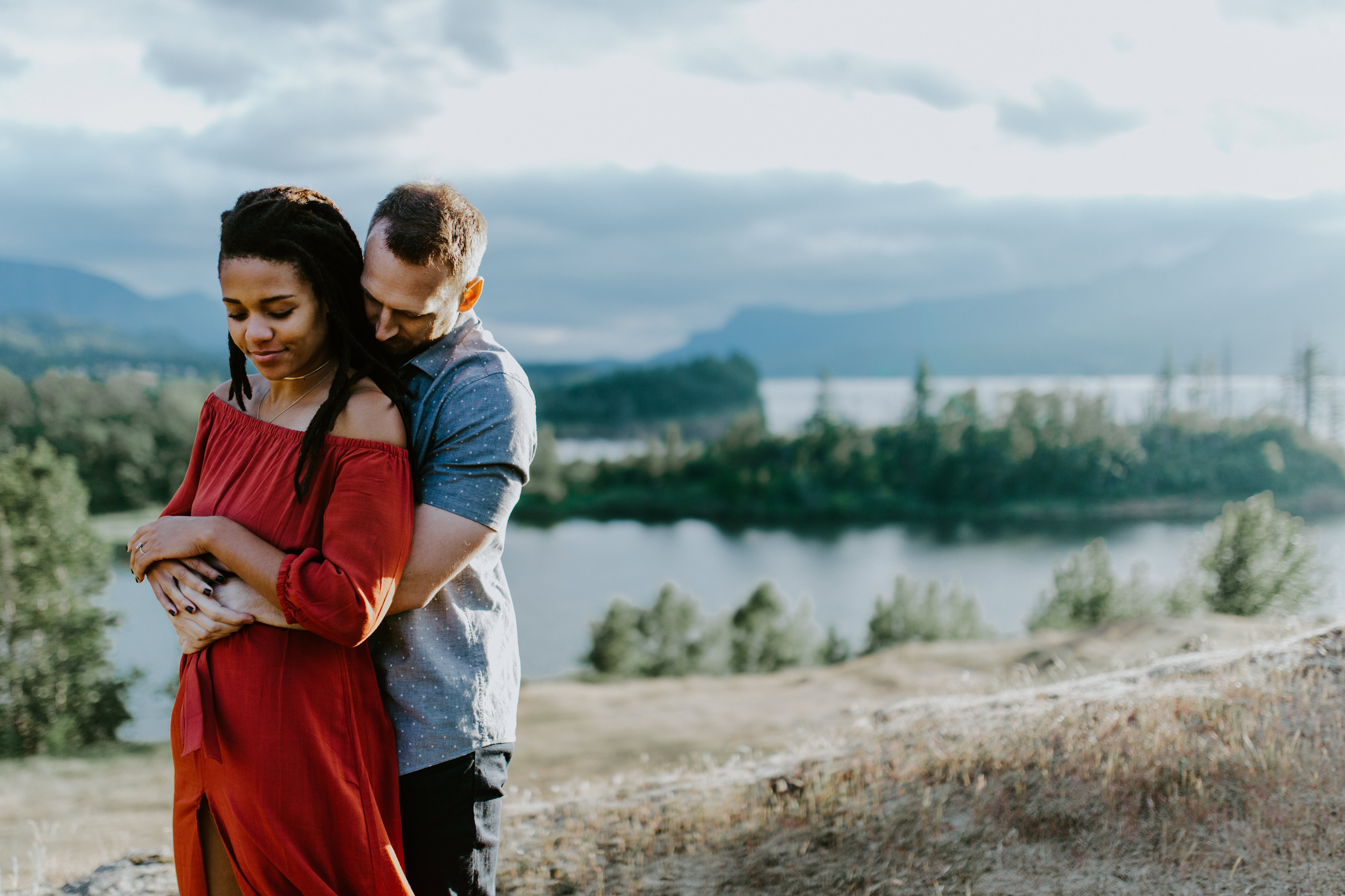 Garrett holds Kayloni as they stand in front of the Columbia River Gorge, Oregon in the background. Engagement photography in Portland Oregon by Sienna Plus Josh.