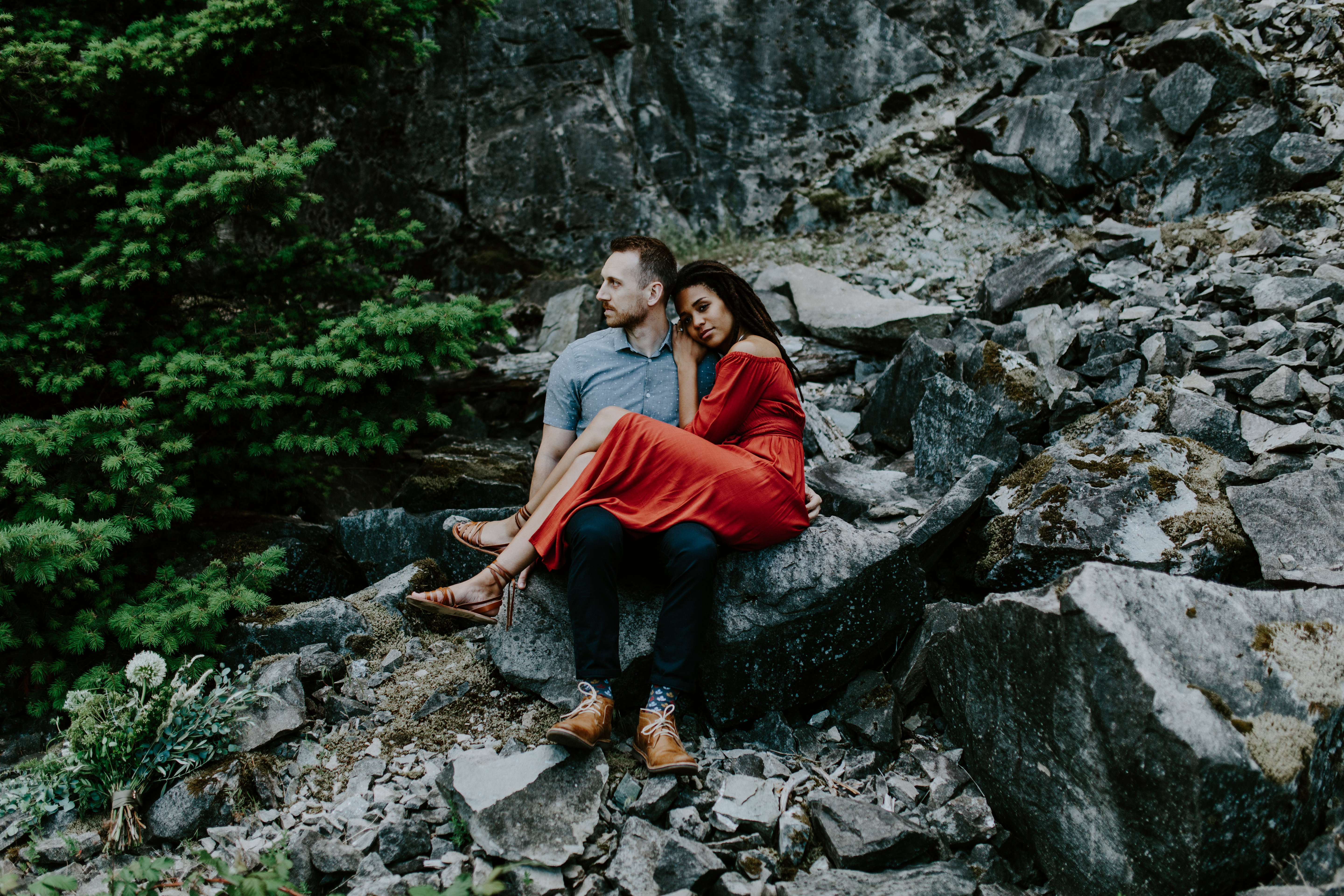 Kayloni and Garrett sit together at the rocks of the Columbia River Gorge, Oregon. Engagement photography in Portland Oregon by Sienna Plus Josh.