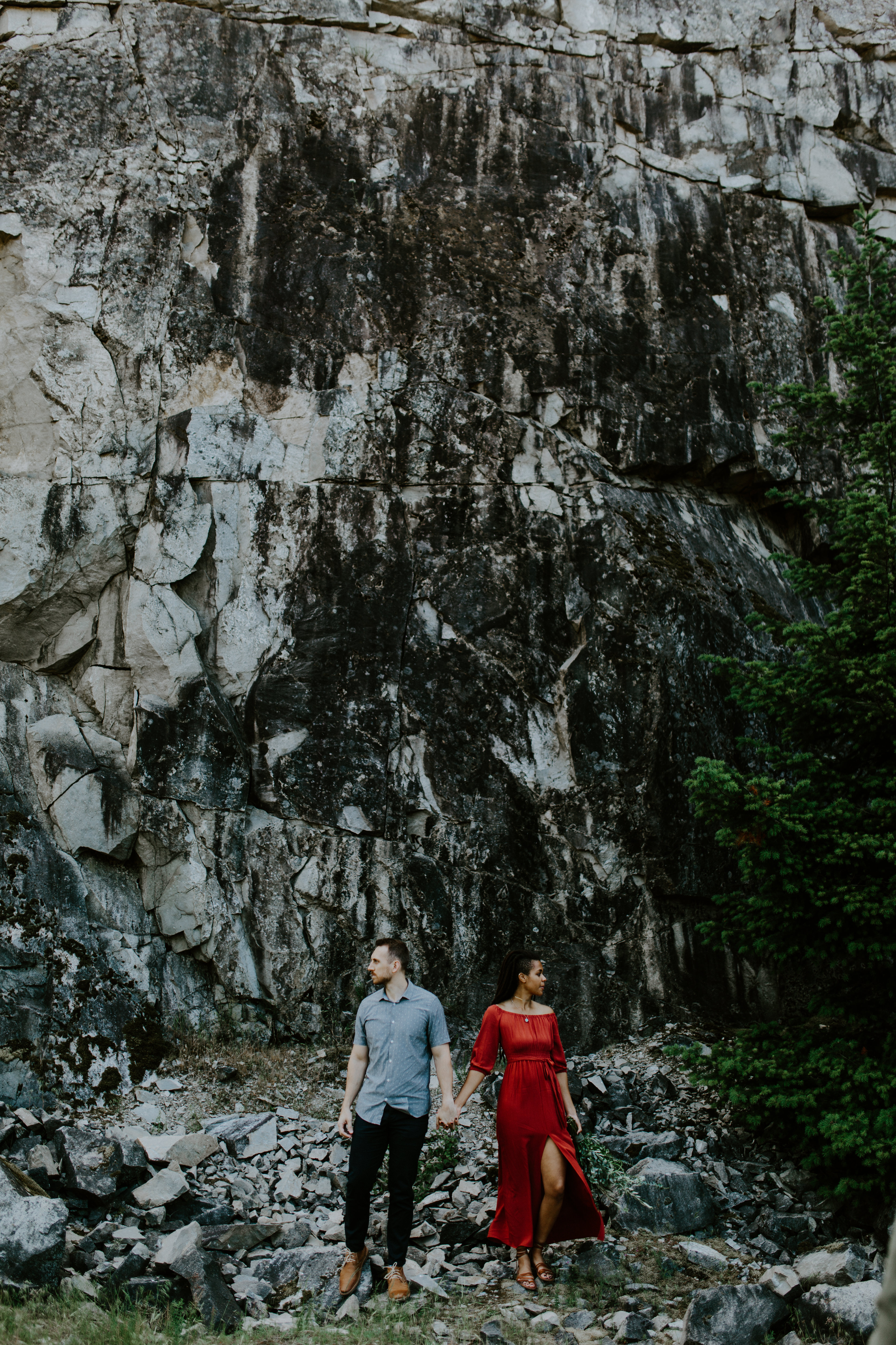 Kayloni and Garrett holding hands and standing in front of the cliff at Cascade Locks, Oregon. Engagement photography in Portland Oregon by Sienna Plus Josh.