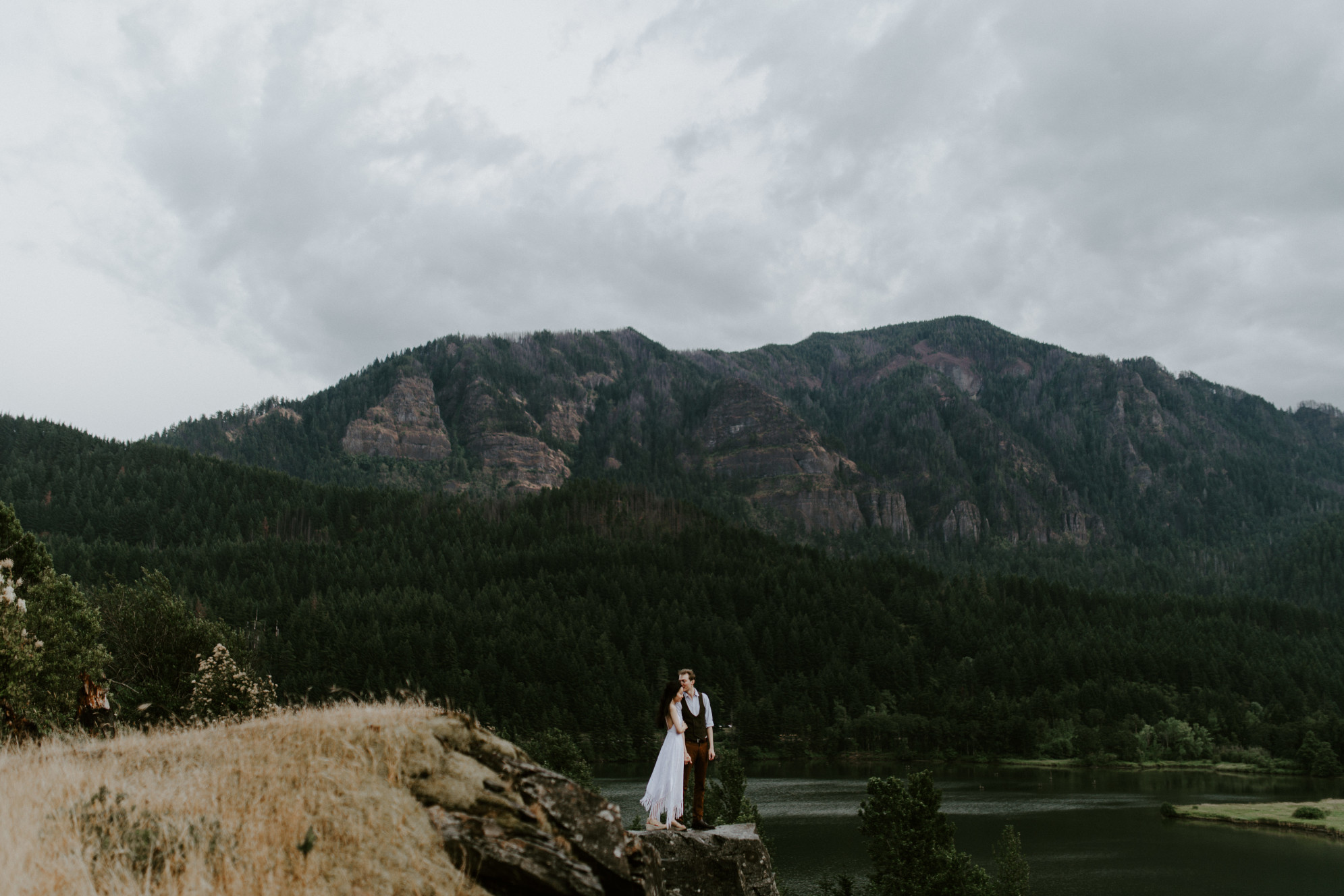 Jacob and Kimberlie stand at the edge of a cliff. Elopement wedding photography at Cascade Locks by Sienna Plus Josh.