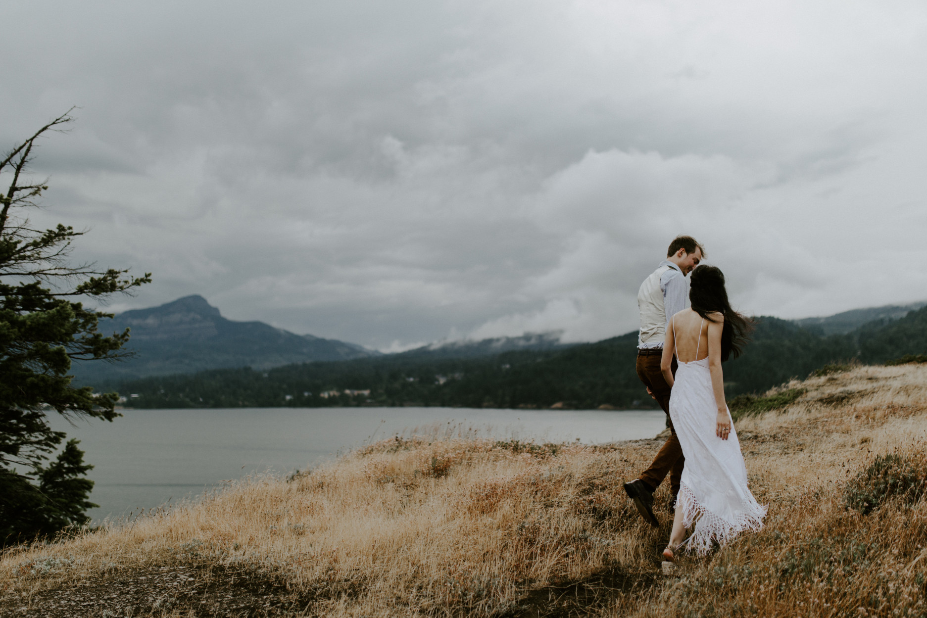 Jacob and Kimberlie walk with a view of a storm in the background. Elopement wedding photography at Cascade Locks by Sienna Plus Josh.