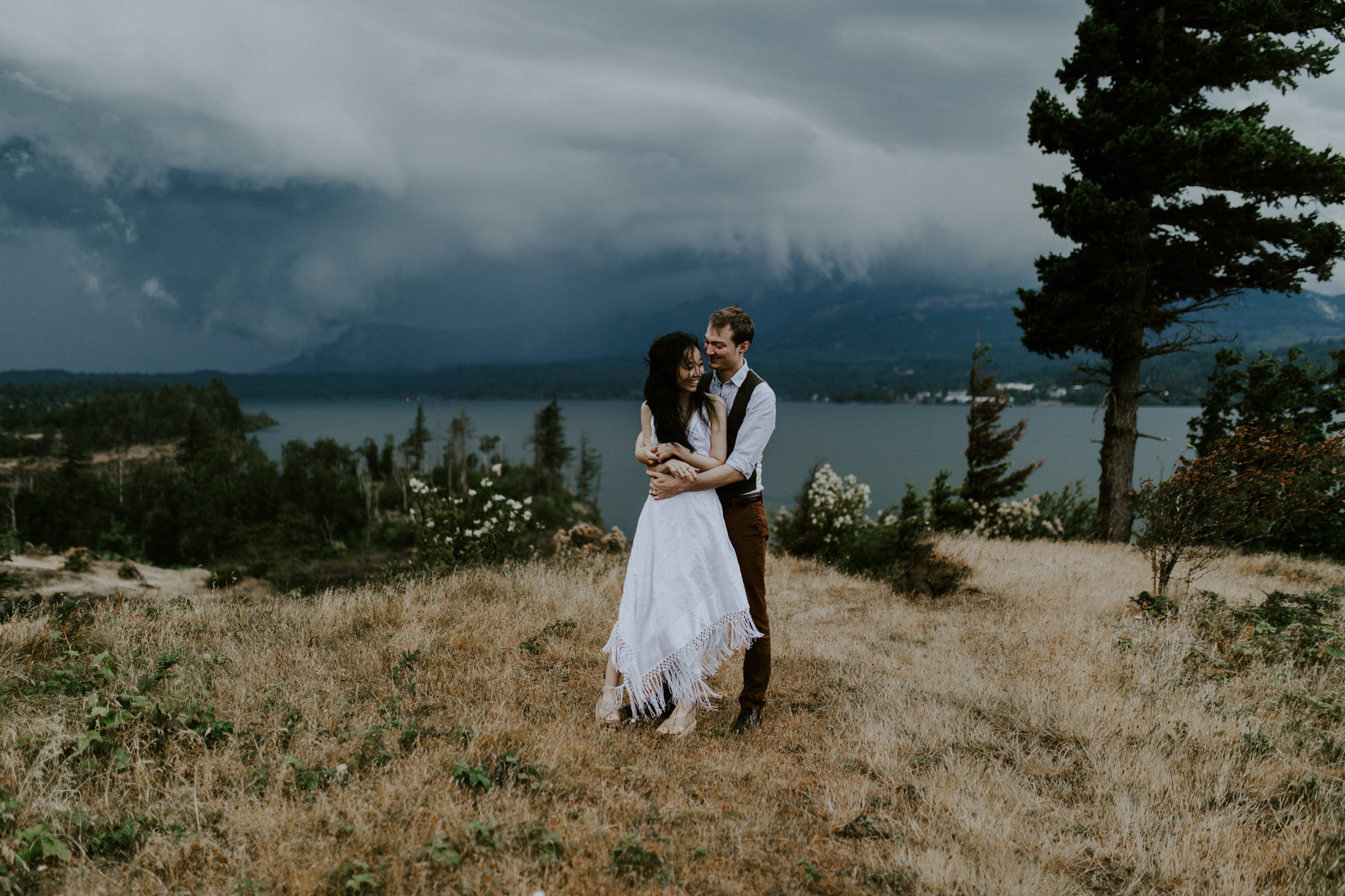 Kimberlie and Jacob stand in front of an incoming storm at the Columbia River Gorge. Elopement wedding photography at Cascade Locks by Sienna Plus Josh.