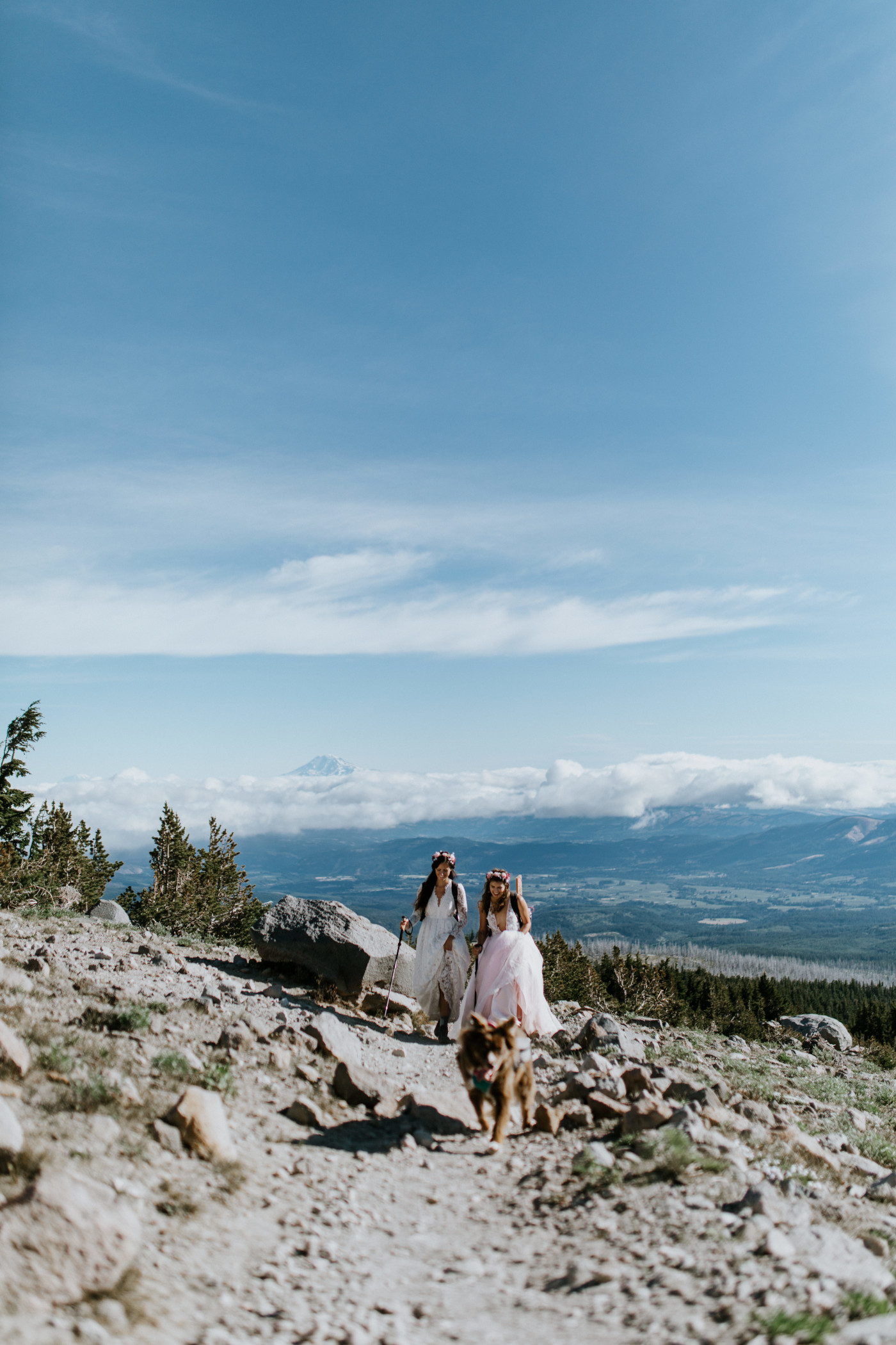 Heather and Margaux hiking up the mountain with a vast view behind them. Elopement photography at Mount Hood by Sienna Plus Josh.