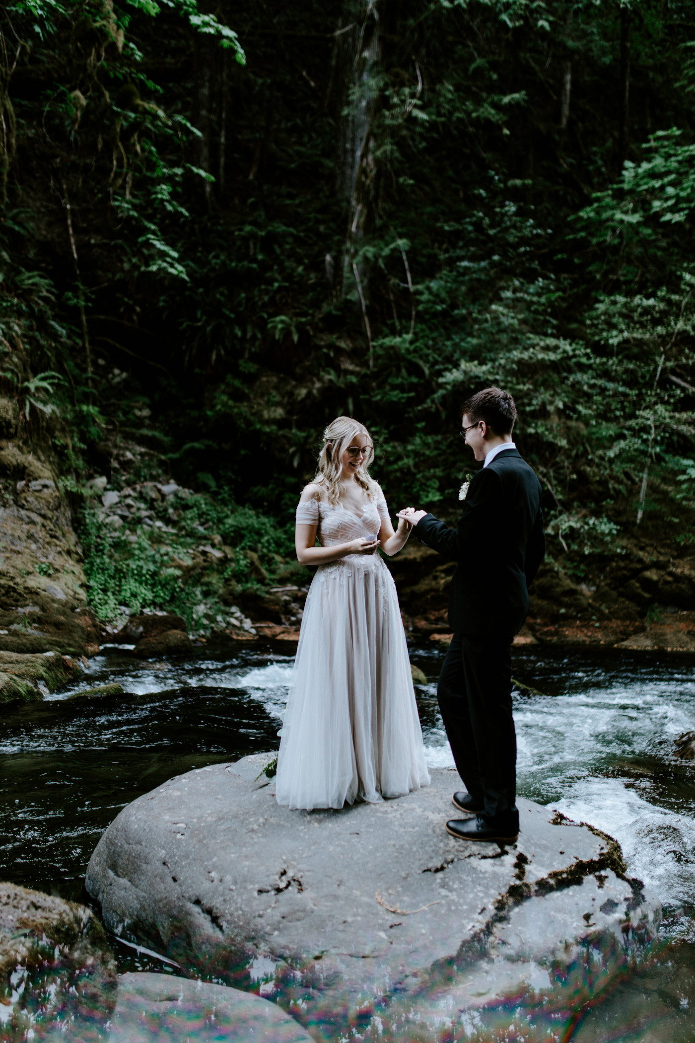 Kylie reads her vows to Corey as they stand in the middle of the river running through Mount Hood National Forest.