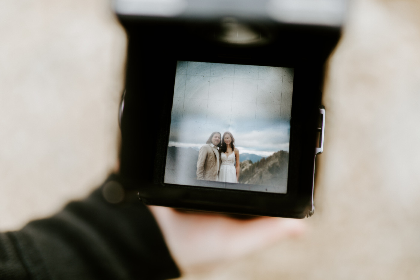 Katrina and Matthew stand for a picture through the view of a film camera at Mount Rainier after their elopement.