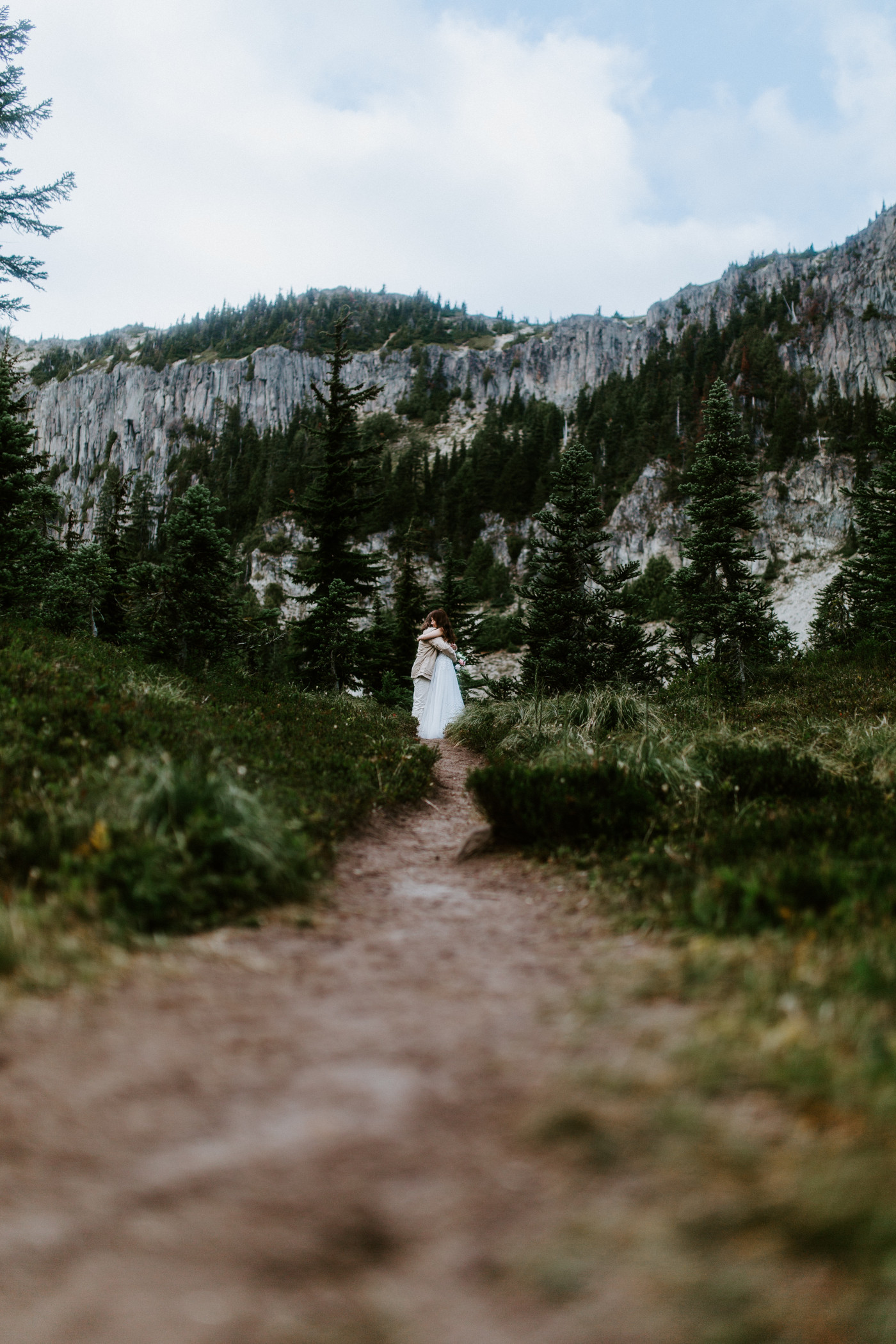 Matthew and Katrina hug on a path in front of Mount Rainier during their elopement ceremony.