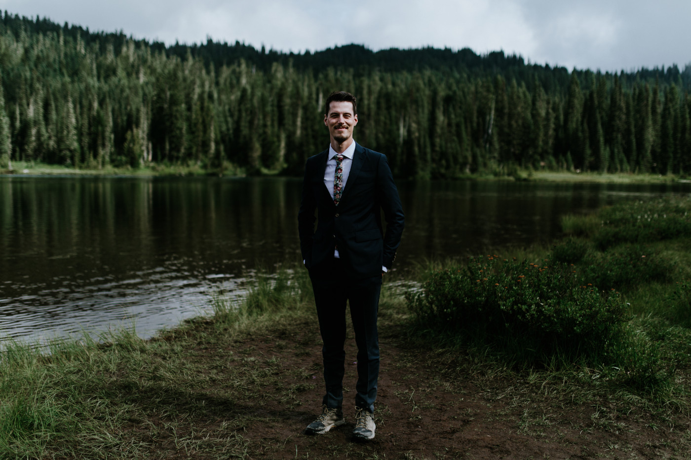 Chad stands near the lake. Elopement photography at Mount Rainier by Sienna Plus Josh.