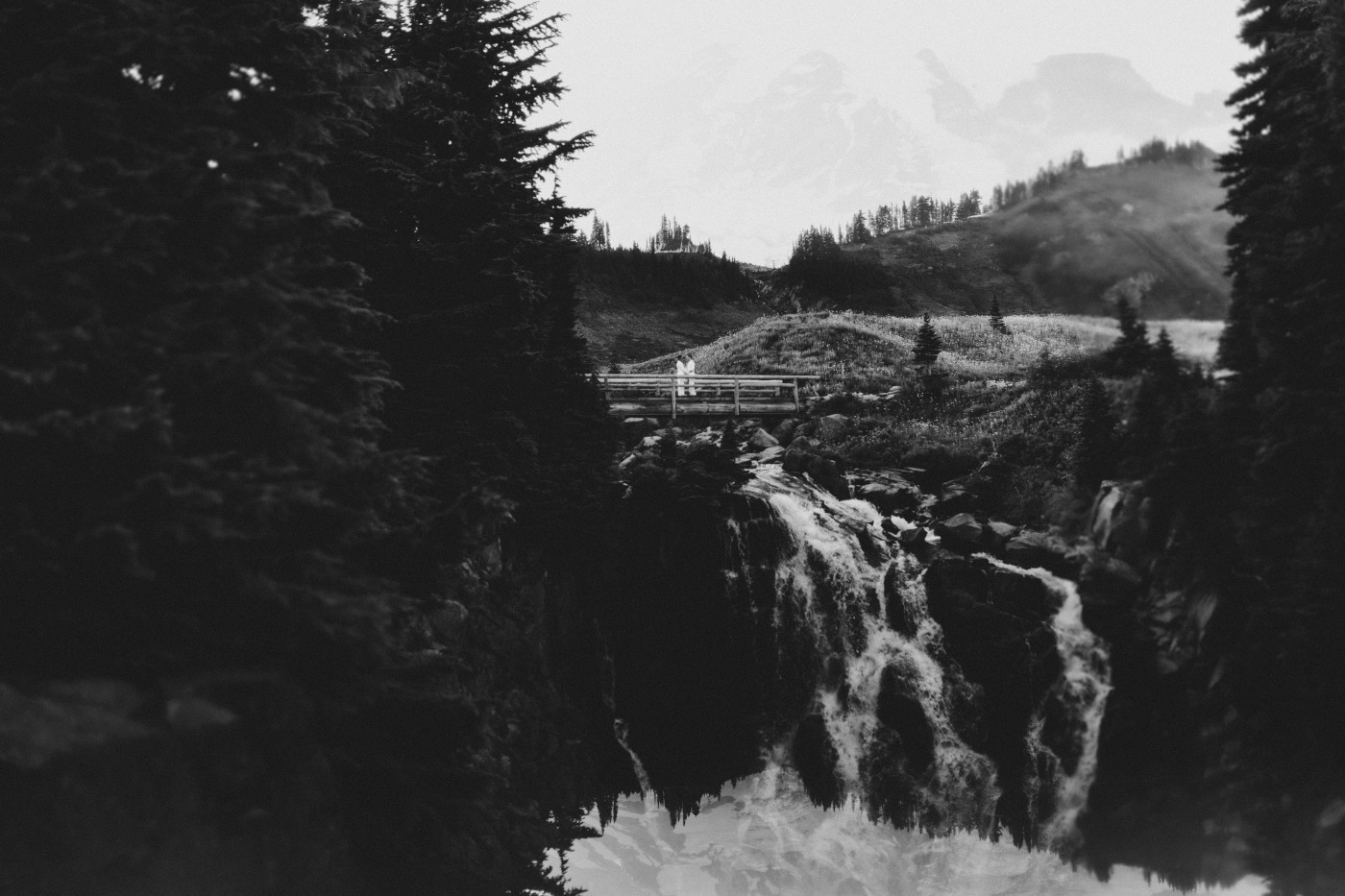 Fred and Brooks stand on the bridge with Mount Rainier behind them.