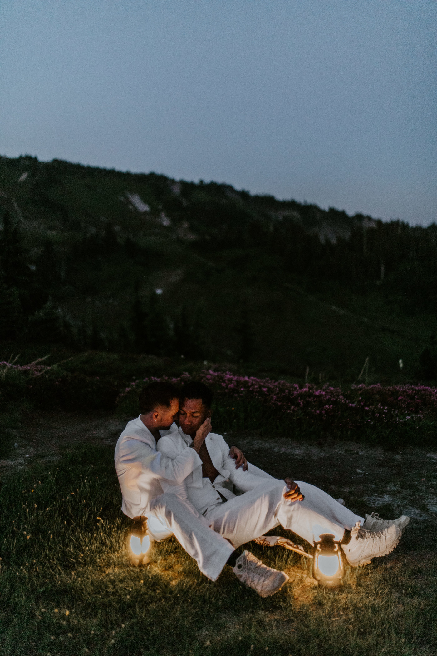 Brooks and Fred sit next to the glow of lanterns in Mount Rainier after their elopement.